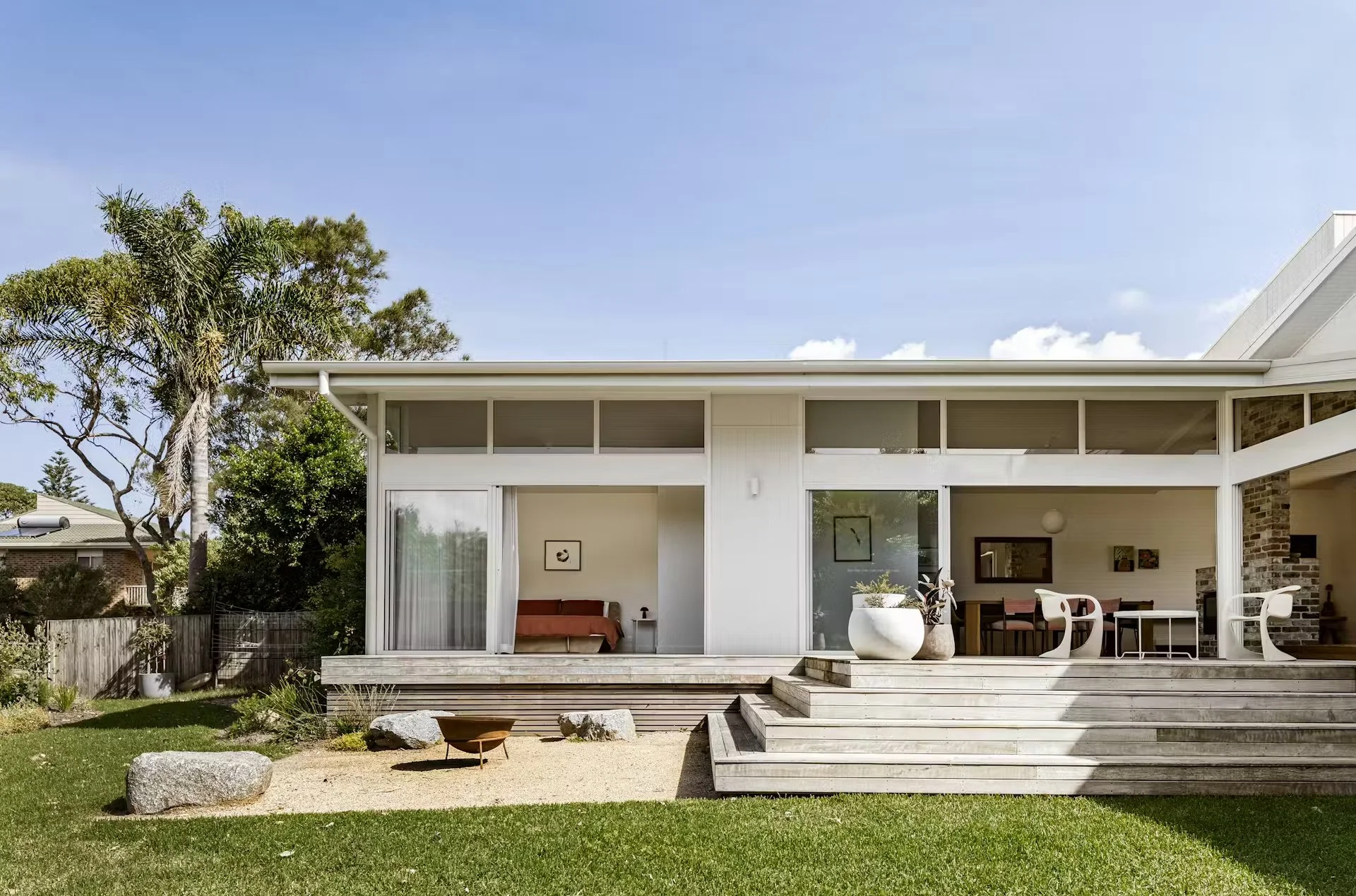 70's Beach House exterior: large patio, white exterior walls, large sliding glass doors, and outdoor furniture under a patio roof.