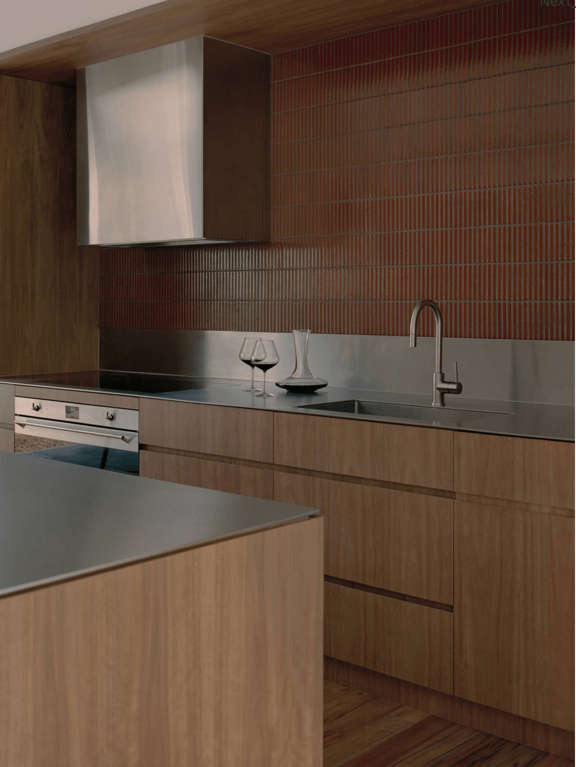 Ironbark House kitchen: Timber cabinets, stainless steel countertop, red tiled backsplash, and minimal decor.