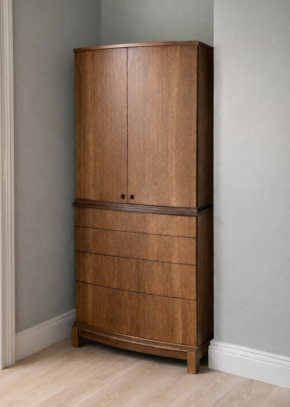 A tall wooden cabinet with closed doors and drawers, placed in a corner of a room with light-colored walls and flooring.