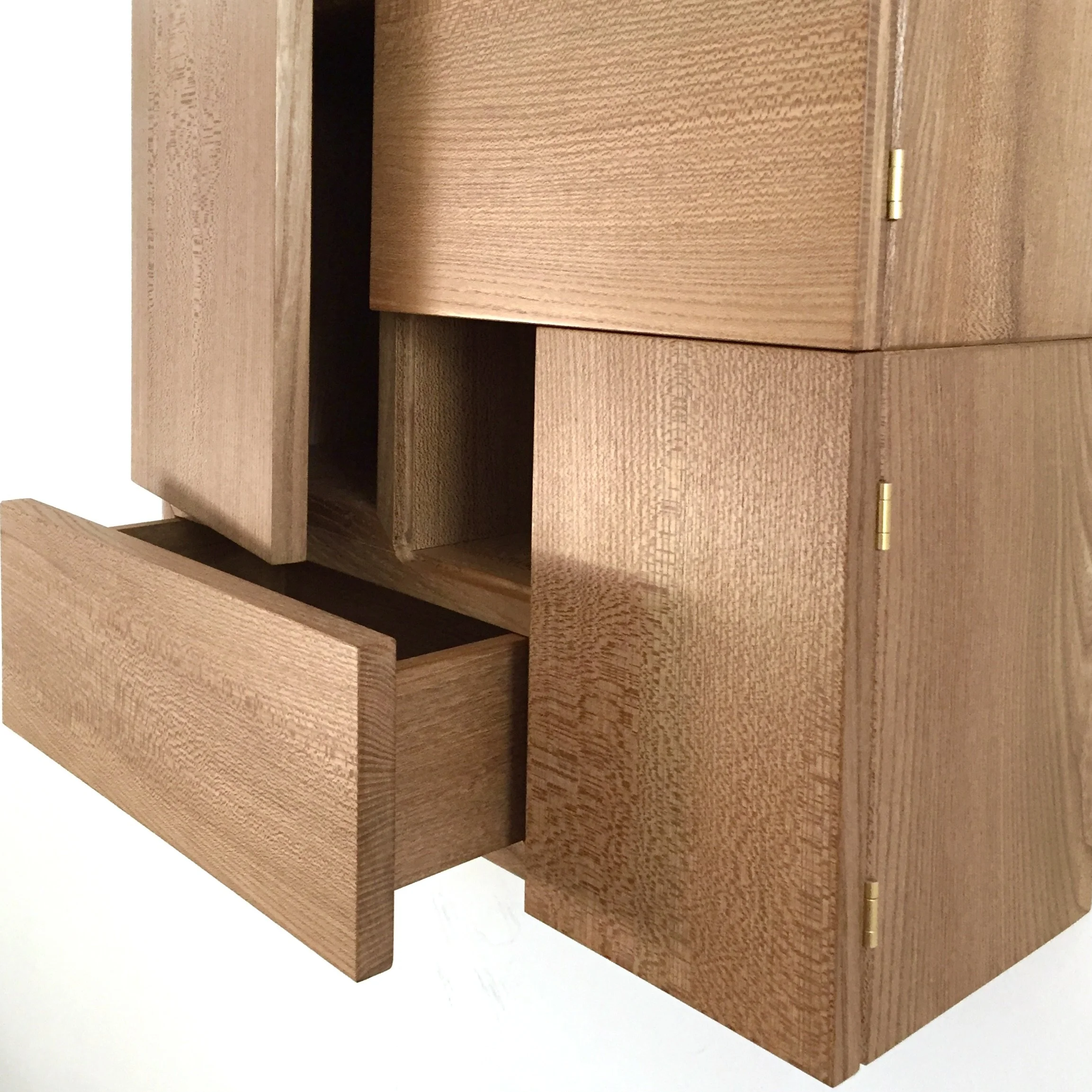 Close-up of a wooden cabinet with one drawer open, showing a simple, modern design and natural wood grain.