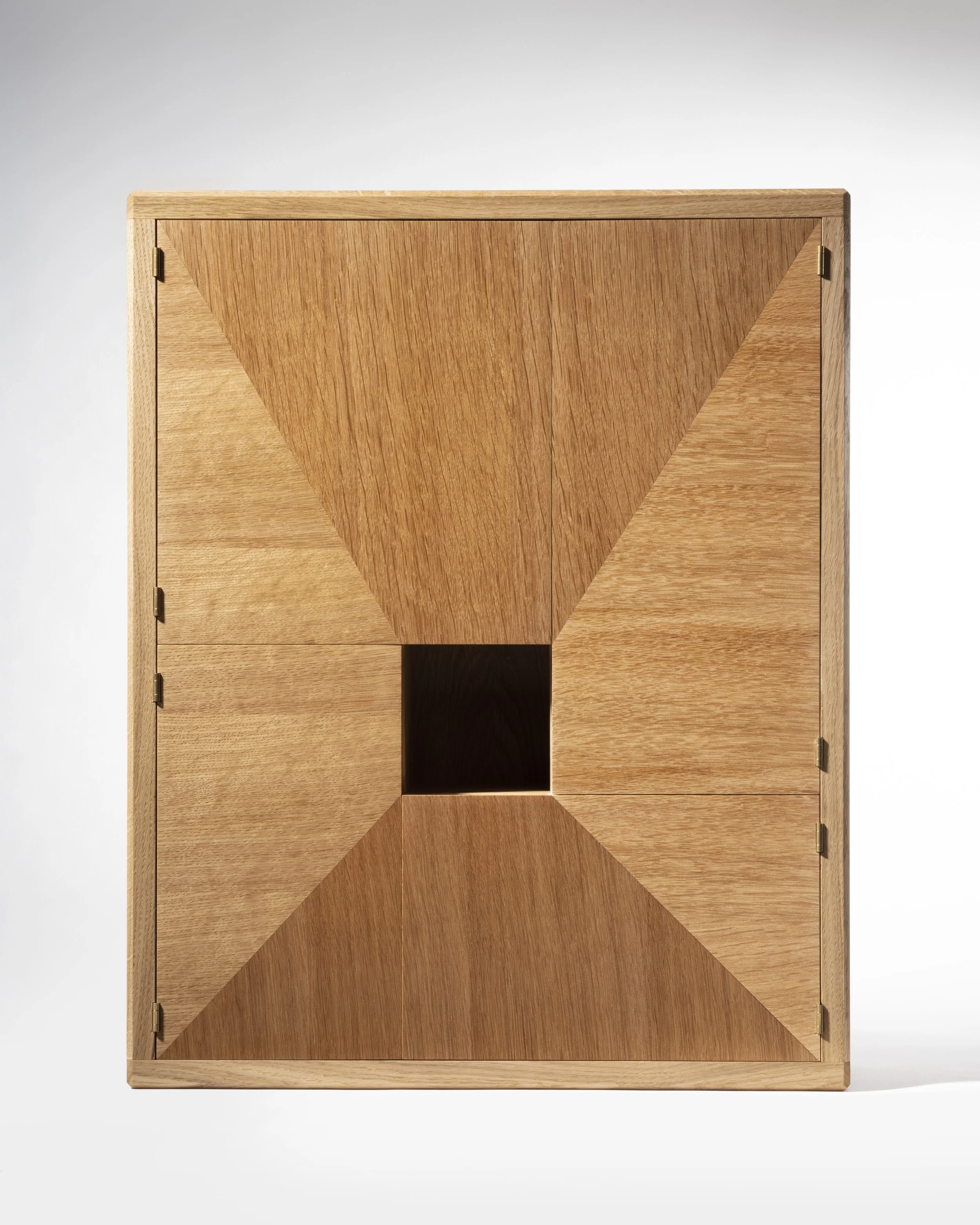 A wooden cube with geometric patterns on its surfaces and a hollow square opening in the center.