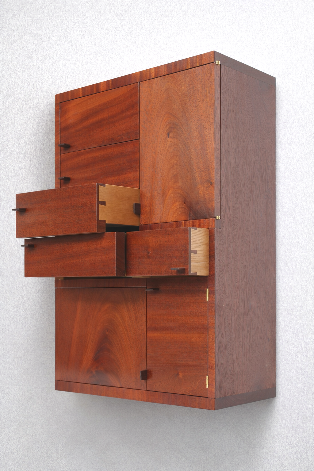 Mid-century modern wooden cabinet with multiple drawers and compartment doors mounted on a plain white wall.