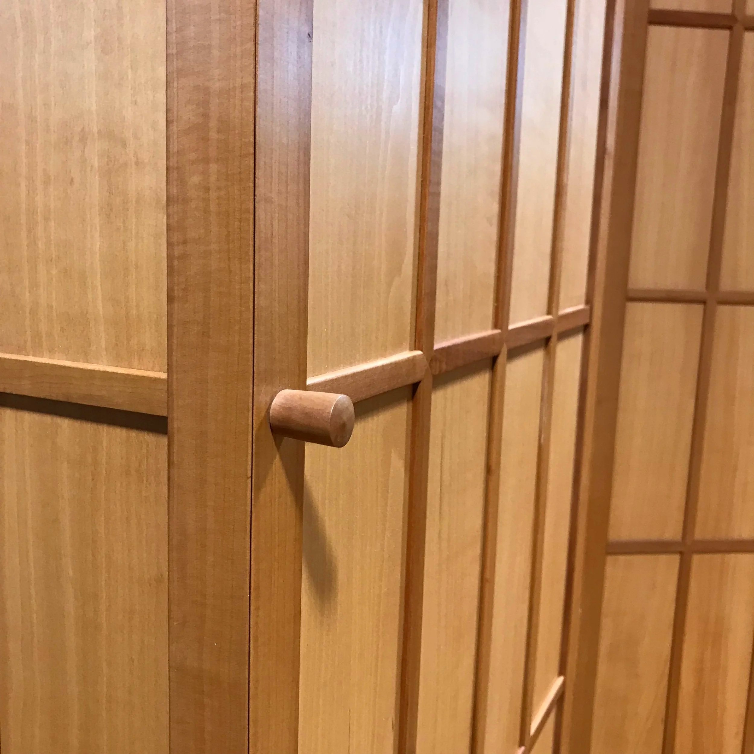 Close-up view of a wooden door with a round wooden handle, featuring vertical and horizontal wooden panels.