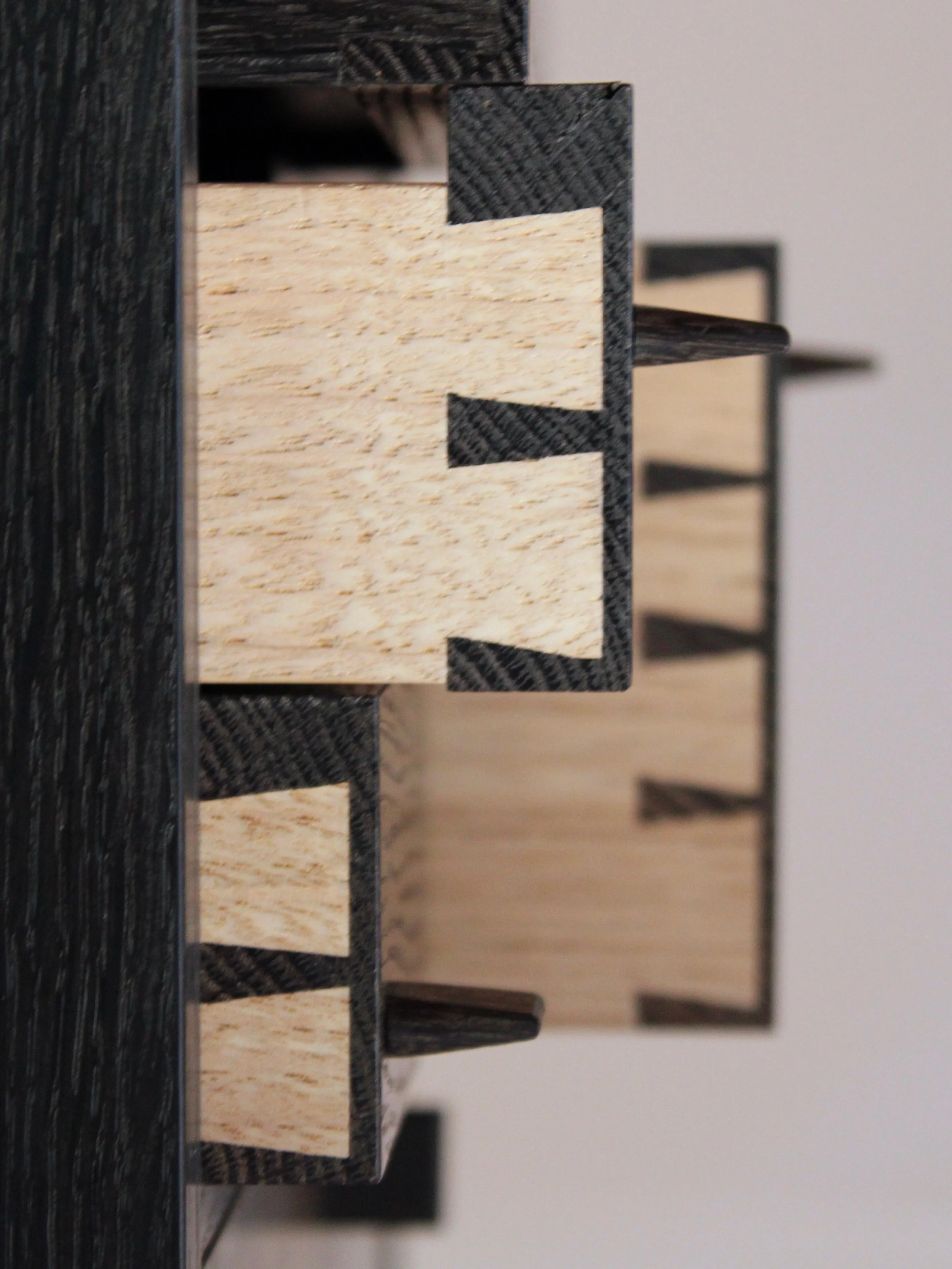 Close-up of a wooden domino with black and natural wood colors, showing part of a domino set.