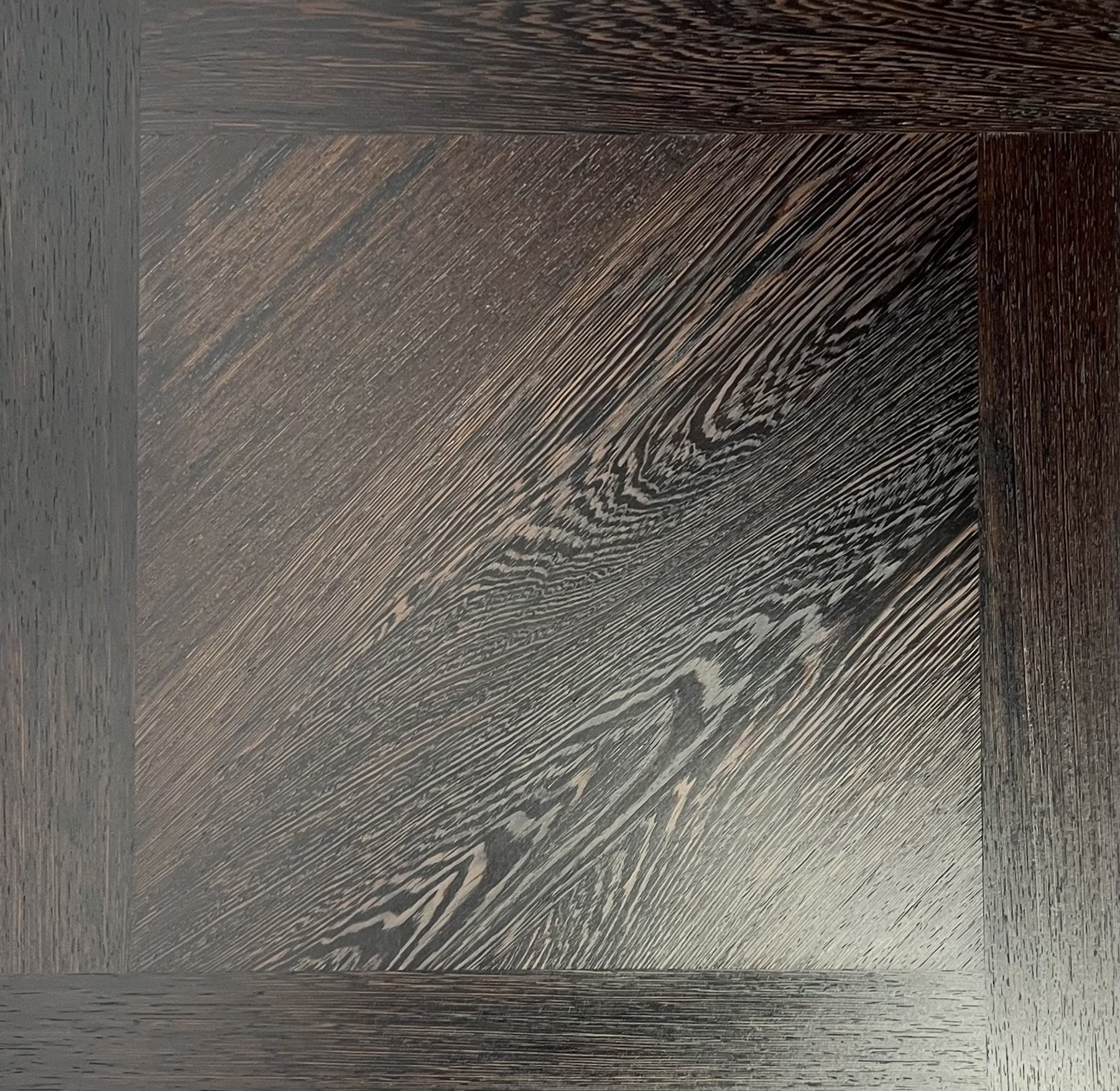 Close-up of a dark stained wooden surface with visible wood grain patterns.