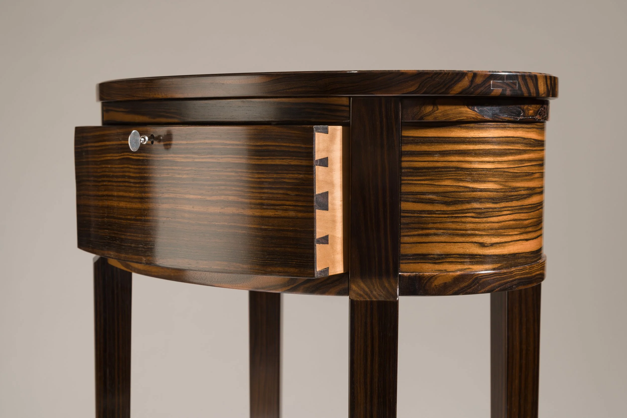 Close-up of a wooden table with a rounded edge, showcasing a wood grain pattern and a connecting joint.