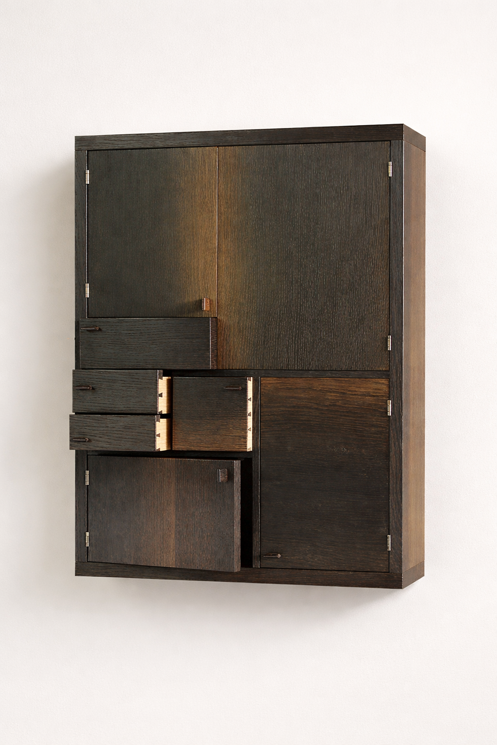 Dark wooden cabinet with multiple doors and drawers mounted on a white wall.