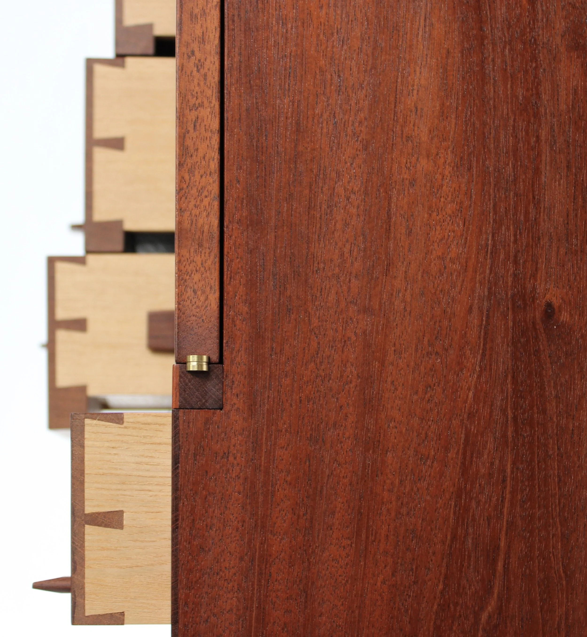 Close-up of a wooden cabinet with multiple drawers, showing detailed wood grain and small brass hardware, against a white background.