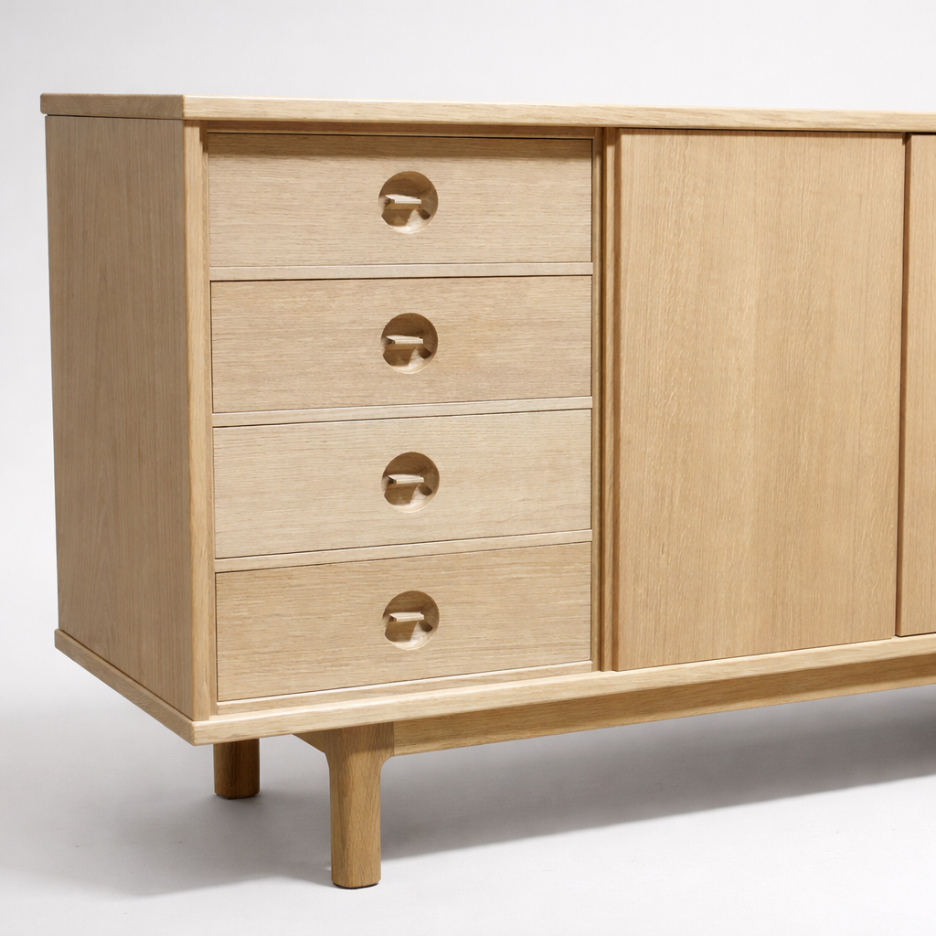 Light wood dresser with four drawers on the left and two sliding doors on the right, standing on four rounded legs.