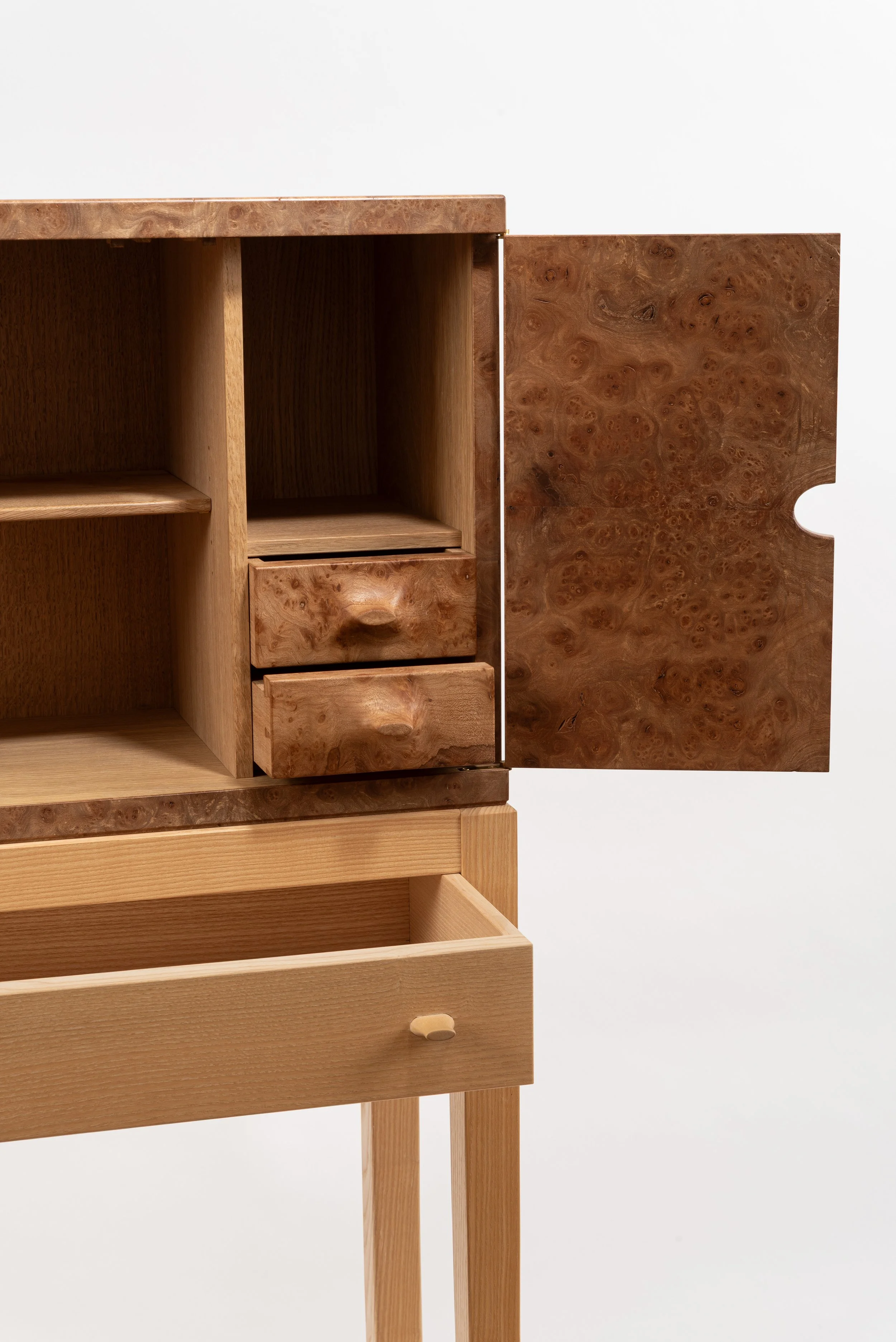Part of a wooden cabinet with open and closed drawers and compartments, made of different types of wood with a natural finish.