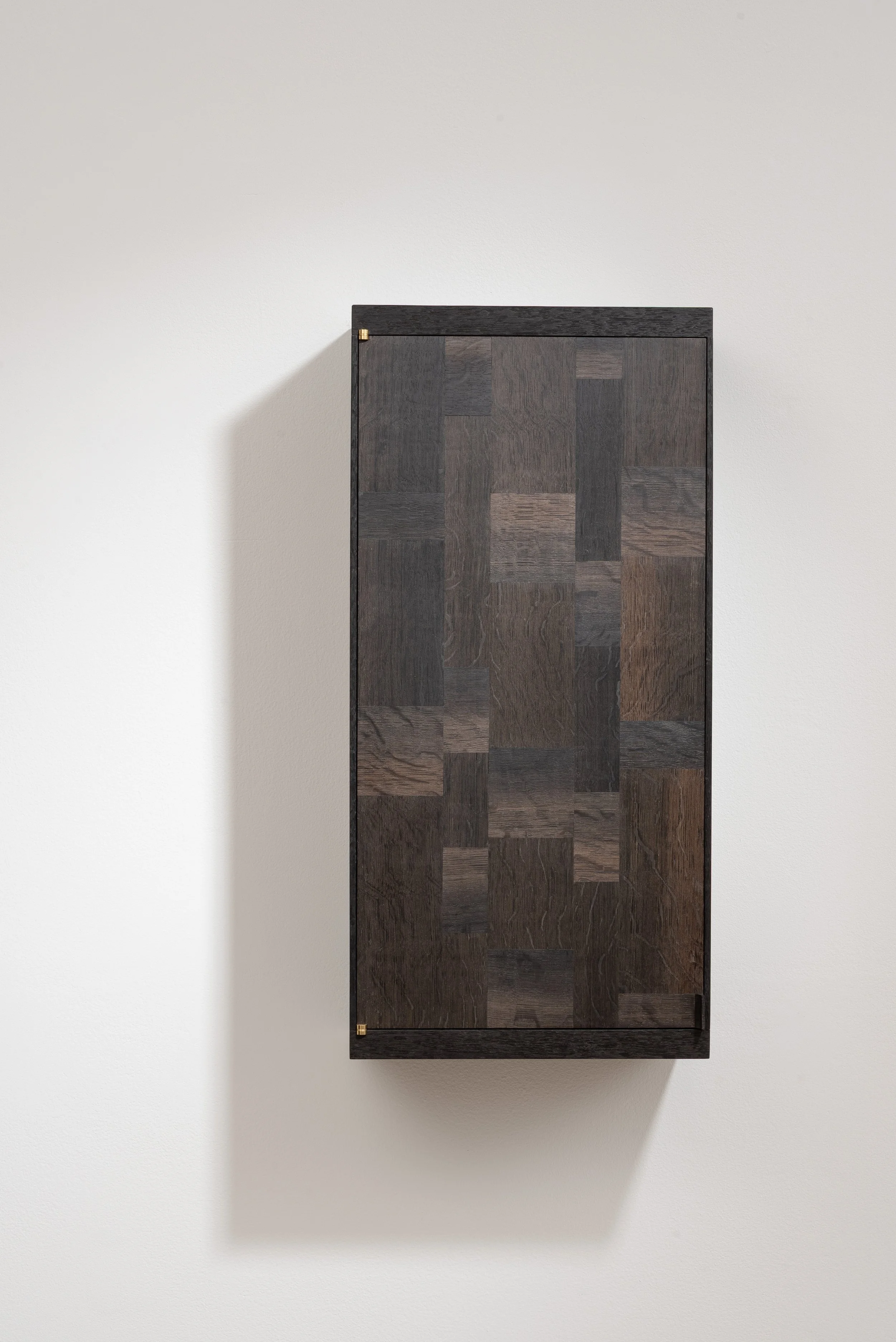 A dark wooden cabinet with a textured pattern on the door, mounted on a white wall.