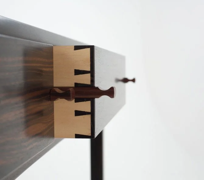 Close-up of the edge of a chessboard with two chess pieces, one dark and one light, viewed from above.