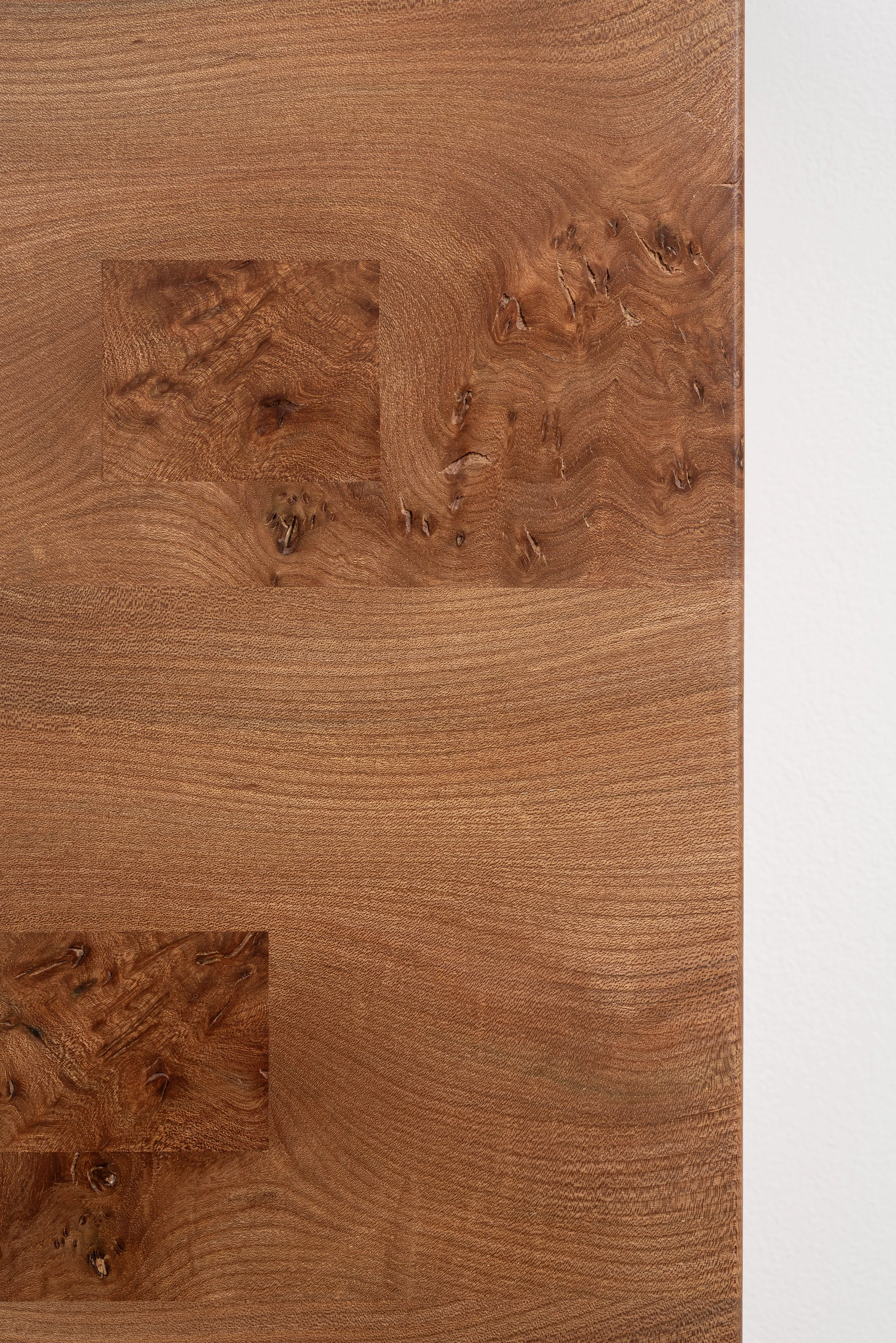 Close-up of a wooden surface with visible wood grain and knots, against a white background.