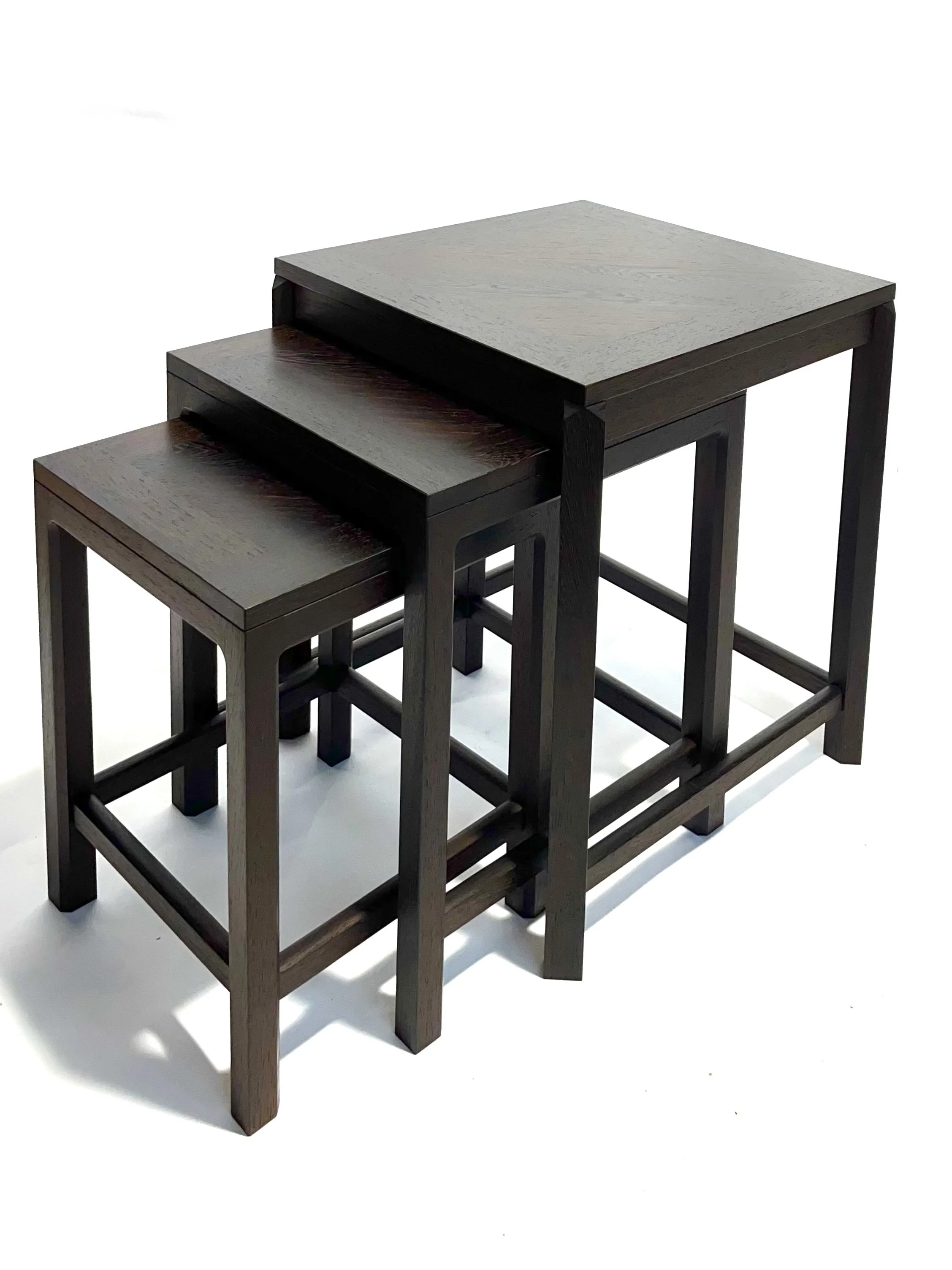 Set of three nested wooden tables with dark stained finish, arranged from largest to smallest against a white background.