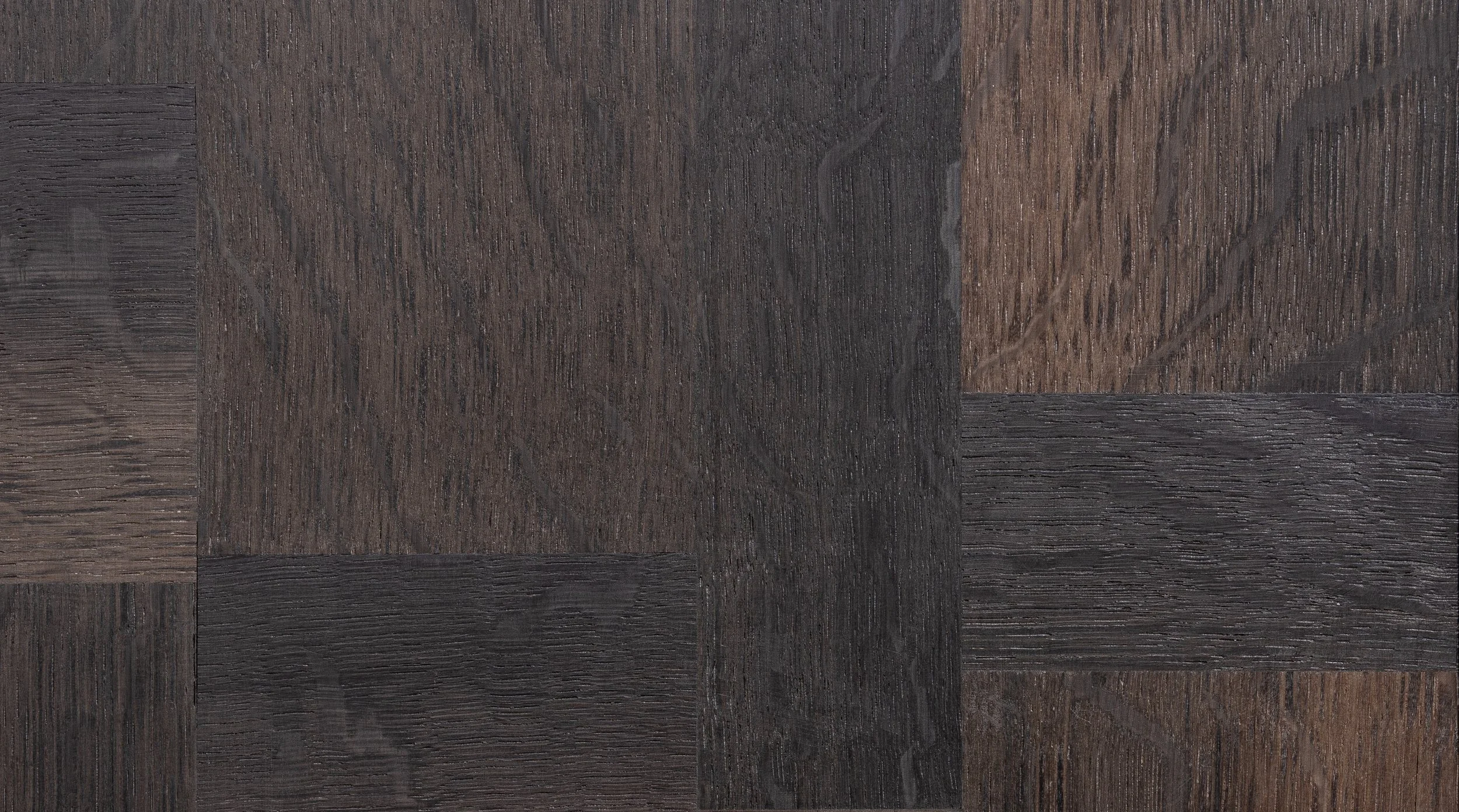 Close-up of a wooden surface with a patchwork pattern of dark brown, black, and reddish wood pieces.