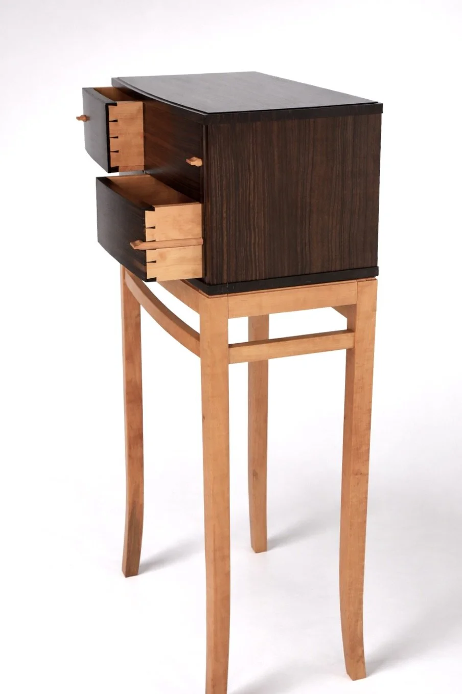 A small wooden cabinet sitting on a taller slender wooden stand with four legs, against a plain white background.