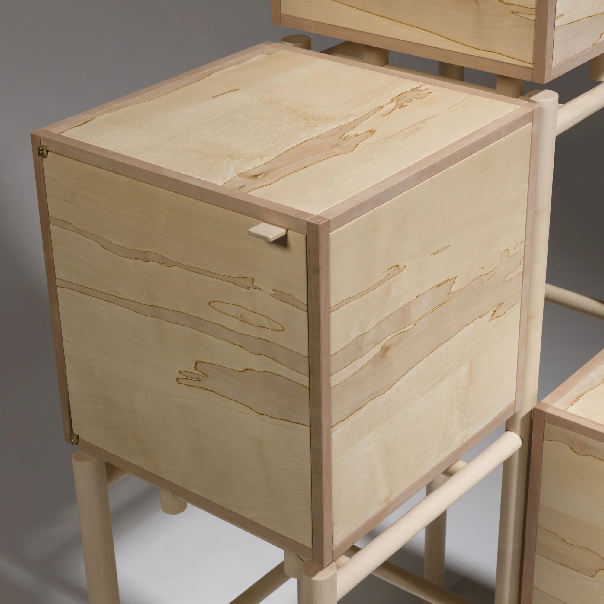 A light-colored wooden storage unit with a single drawer and top surface, supported by a matching wooden frame with light-colored legs.