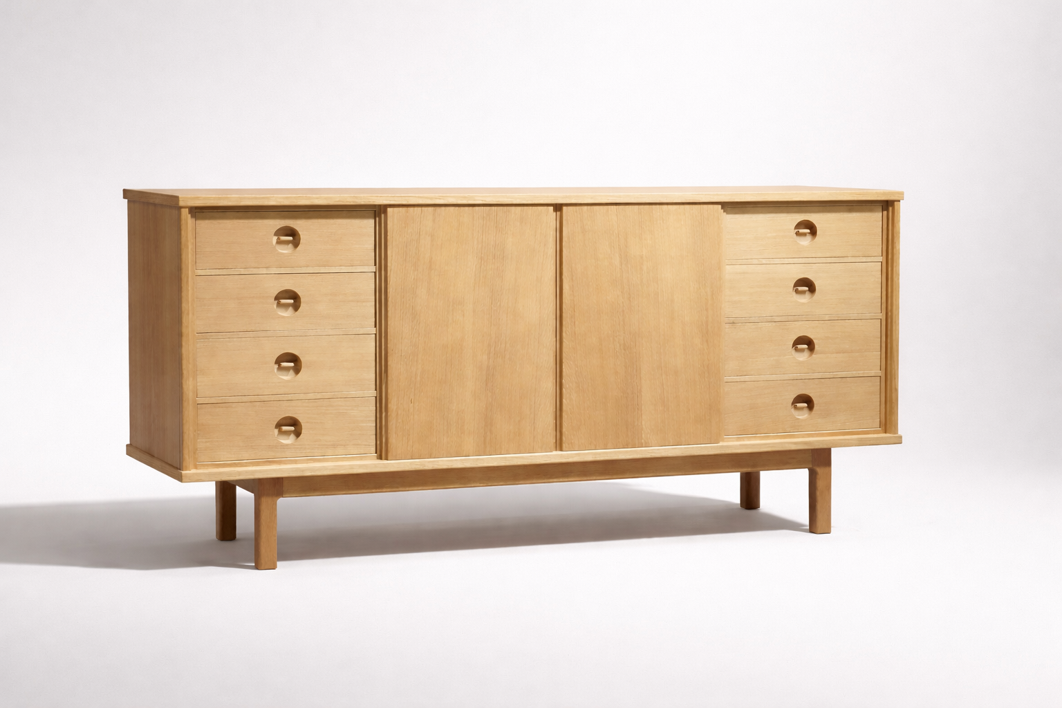 Light wood sideboard with six drawers, three on each side, and two sliding doors in the middle, set against a plain white background.