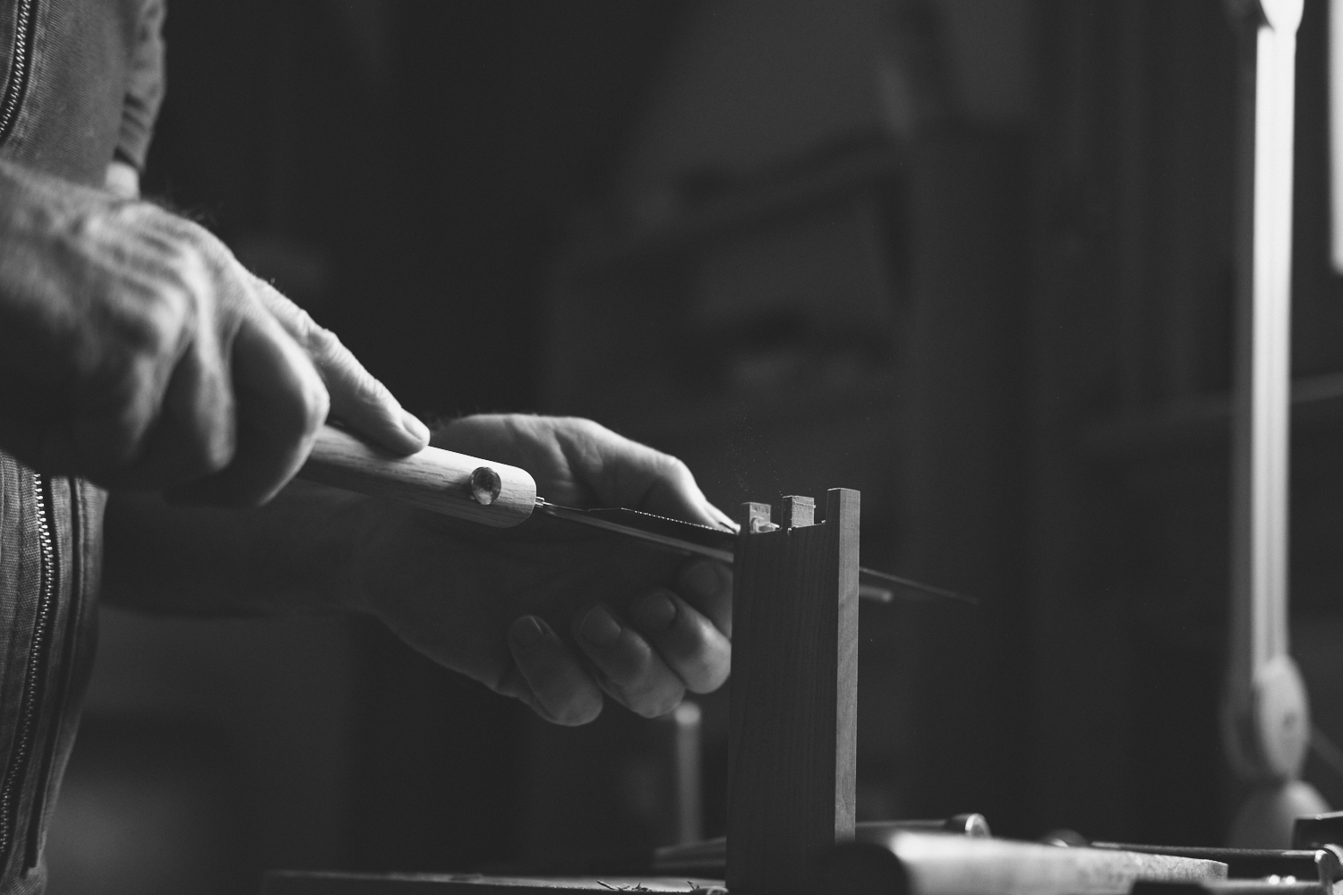 A person using a hand saw to cut a piece of wood.