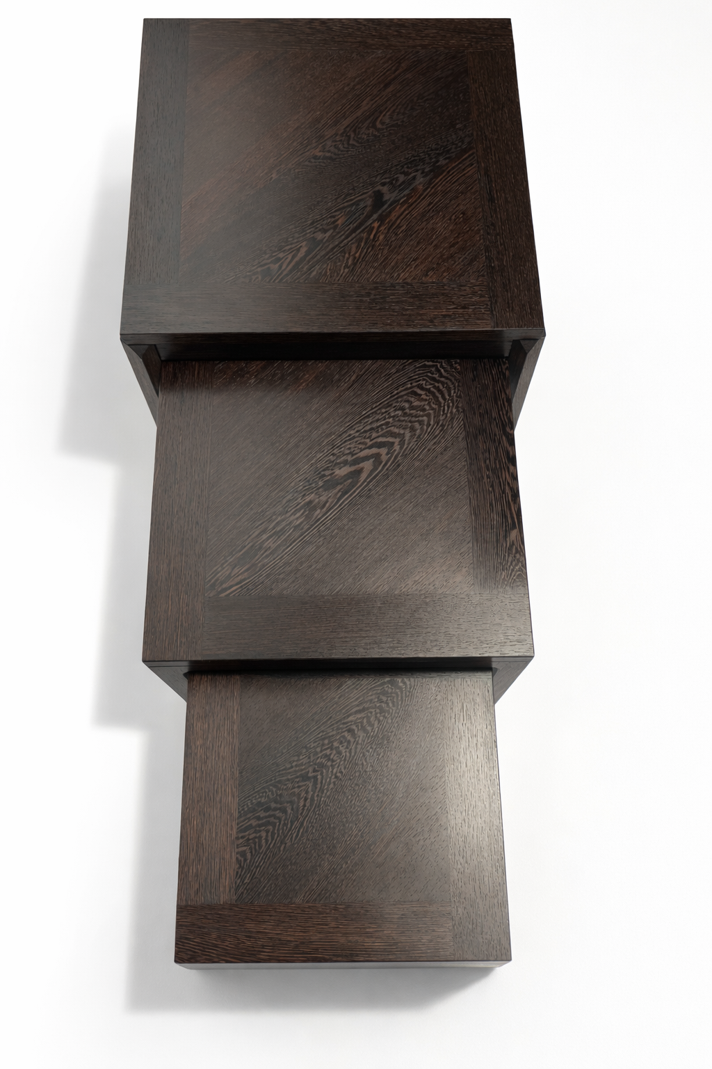Top view of three stacked dark wooden blocks with beveled edges on a white surface.