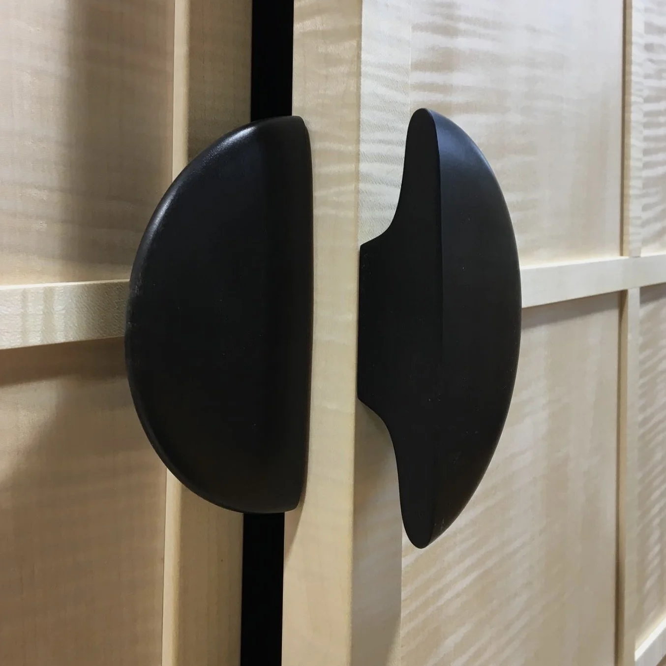 Black door handles attached to a light-colored wooden door.