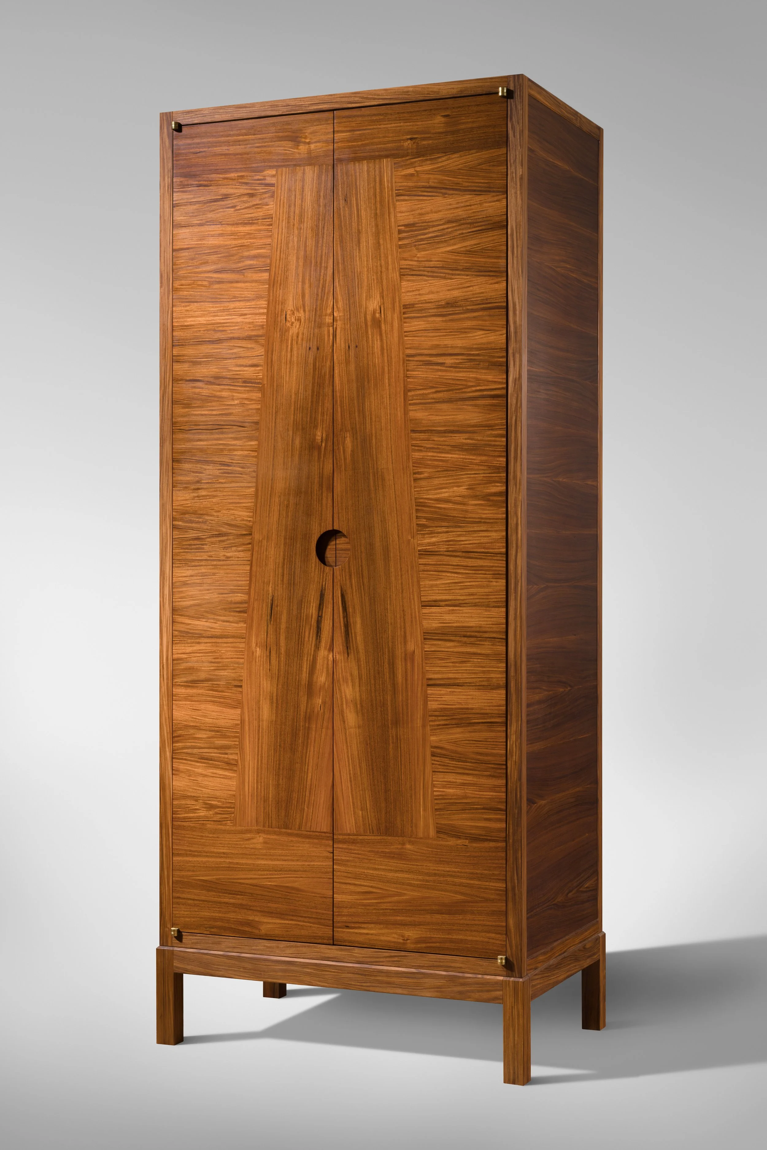 A tall wooden wardrobe with a natural finish and minimal design, standing against a neutral gray background.