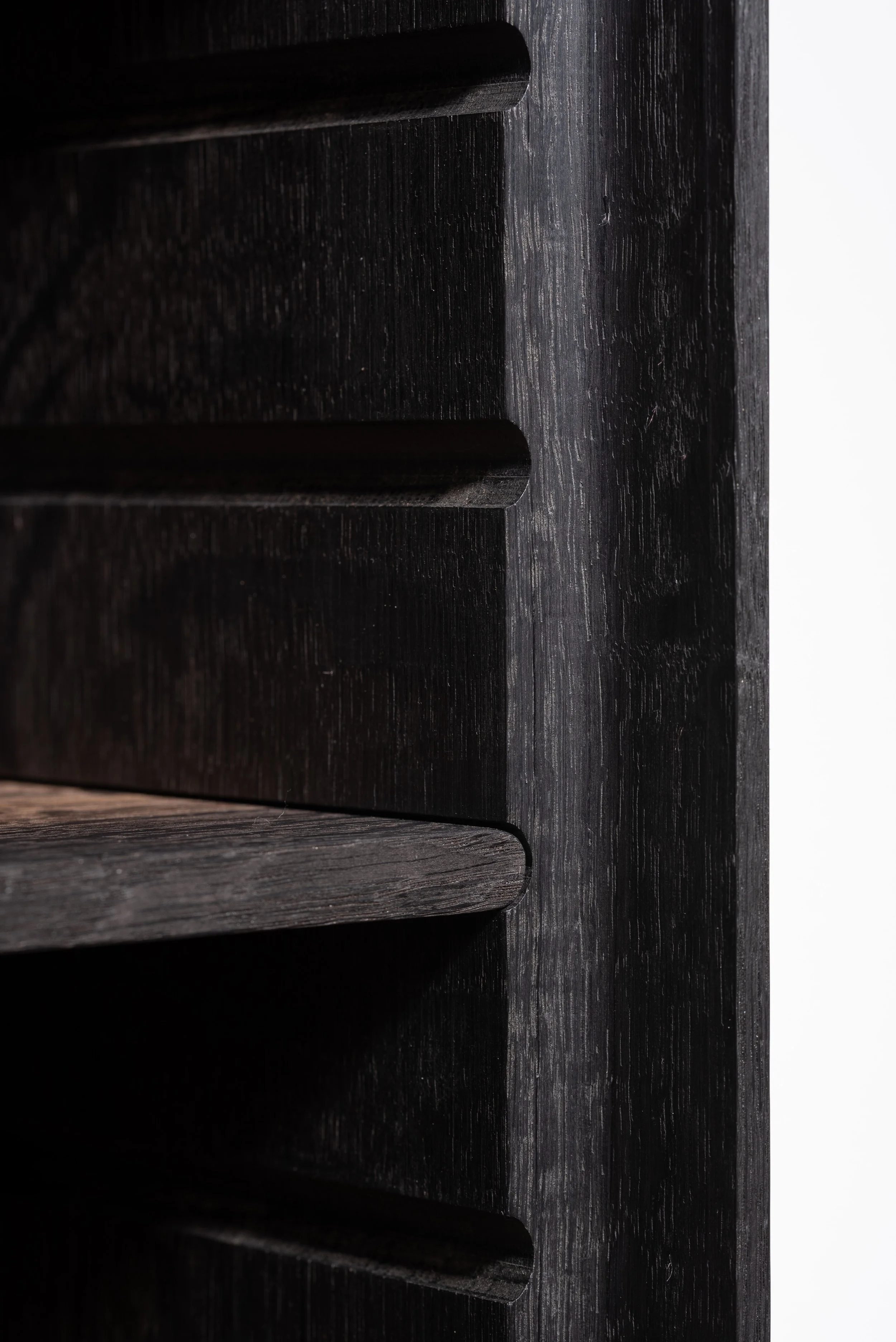 Close-up of dark colored wooden furniture showing horizontal slats or drawers with rounded edges.