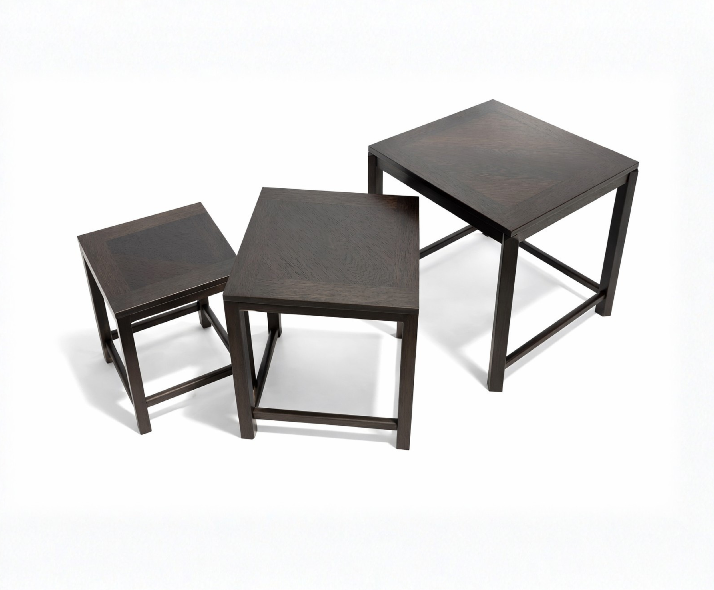 Set of three dark wooden nesting tables on a white background.