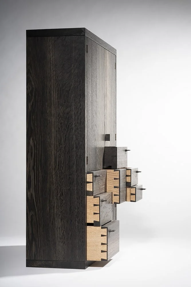 Modern black and natural wood dresser with multiple drawers, set against a plain white background.