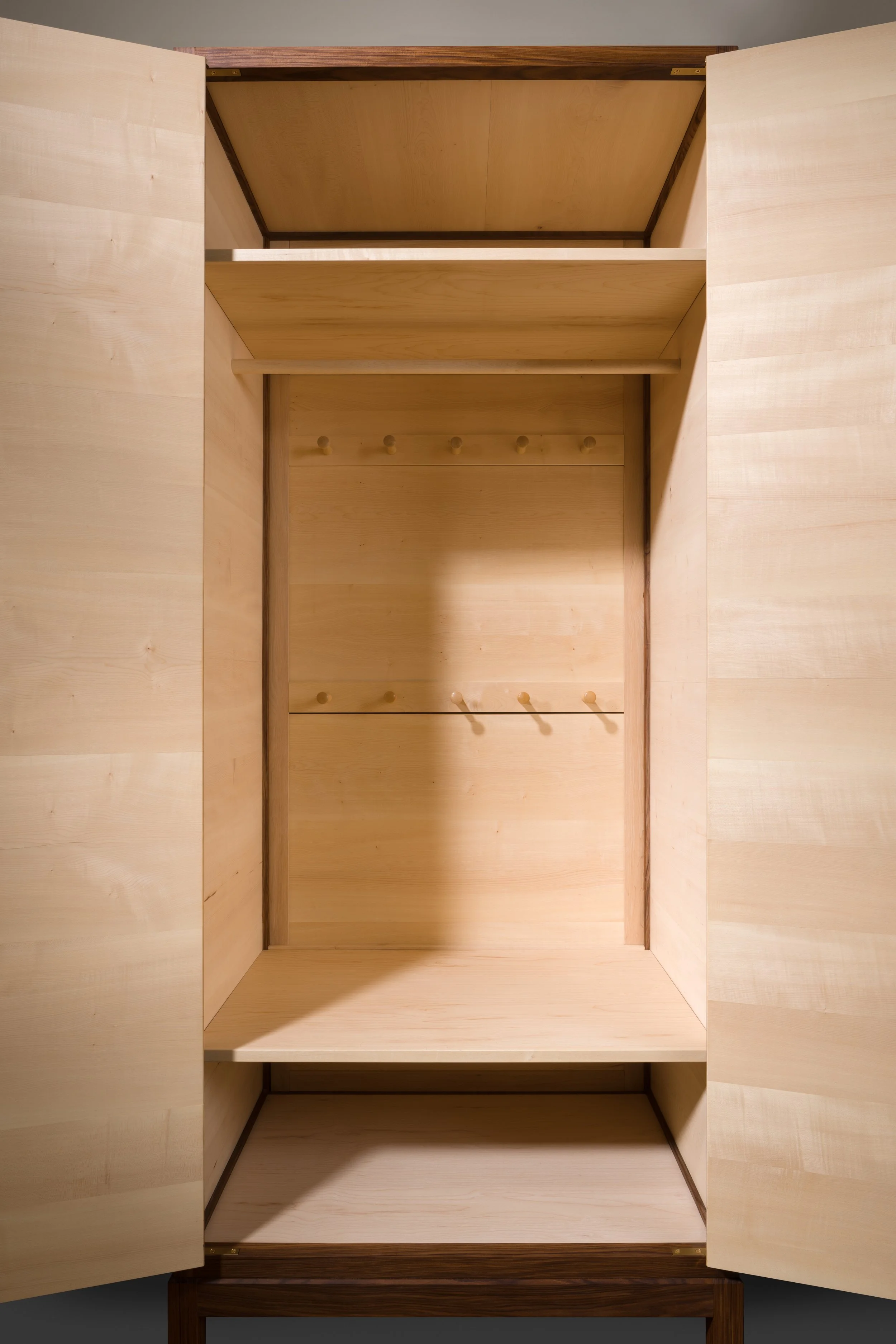 Empty wooden wardrobe with open double doors, shelves, and hooks inside.