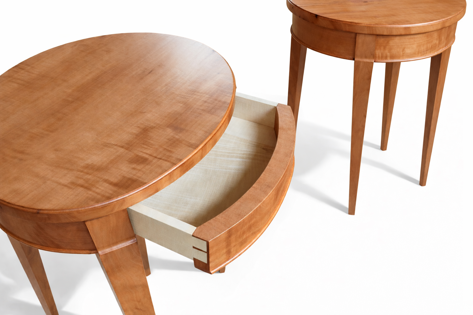 Close-up of two wooden nesting tables, one with a drawer partially open, against a white background.