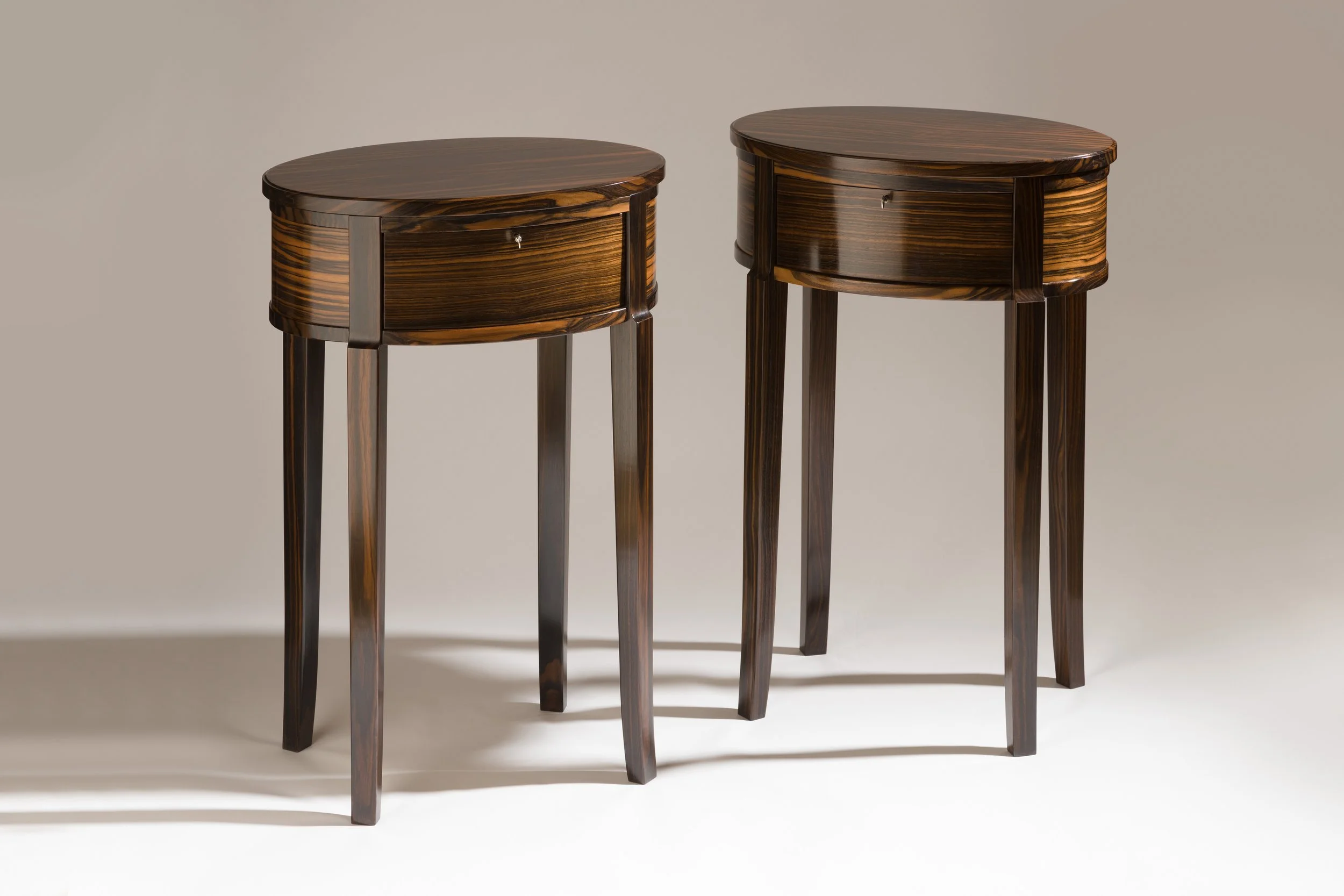 Pair of dark wooden side tables with rounded tops and four legs each, set against a neutral background.