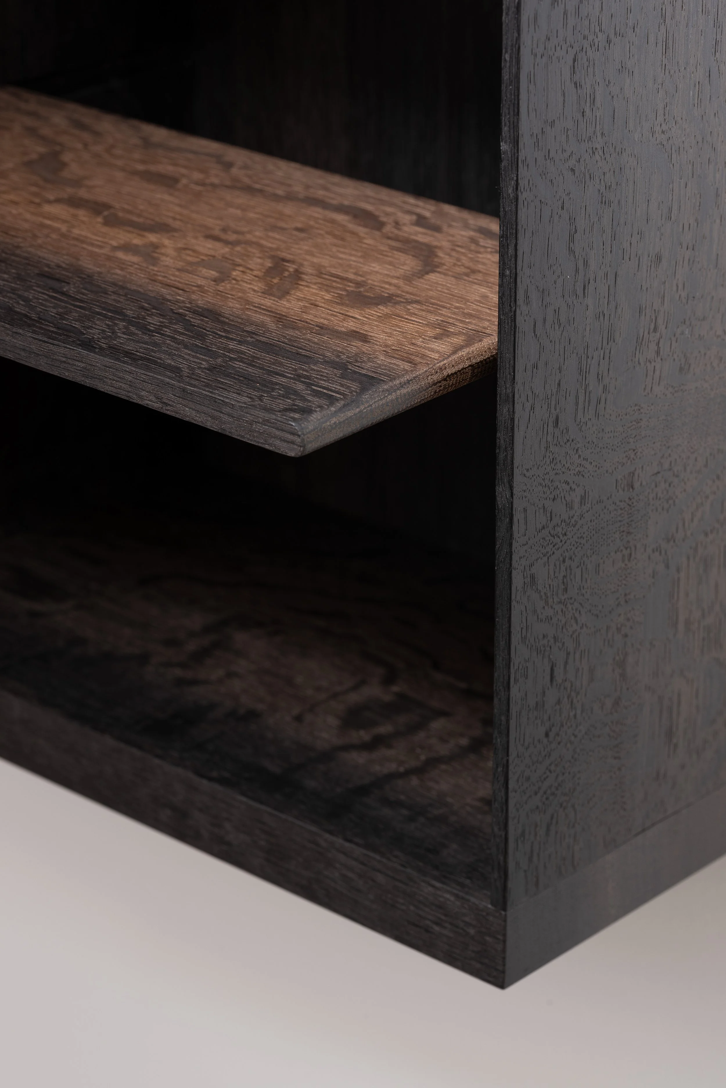 Close-up of a wooden piece of furniture, showing a dark finish with visible wood grain.