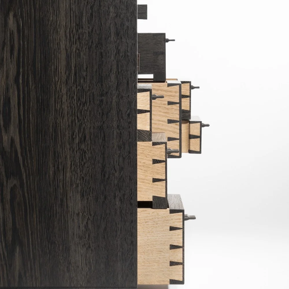 Close-up of a collection of wooden woodworking clamps arranged standing vertically on a dark textured wooden surface with a plain white background.