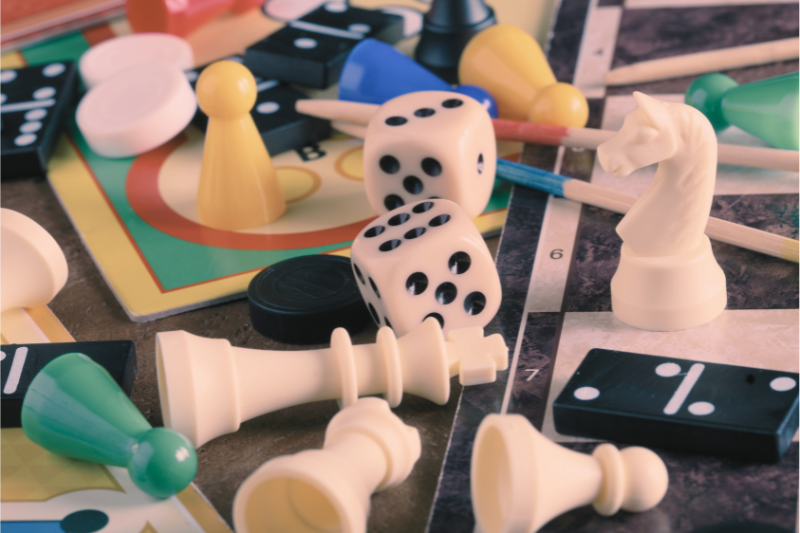Board game pieces including dice, pawns, and a knight chess piece scattered on a table.