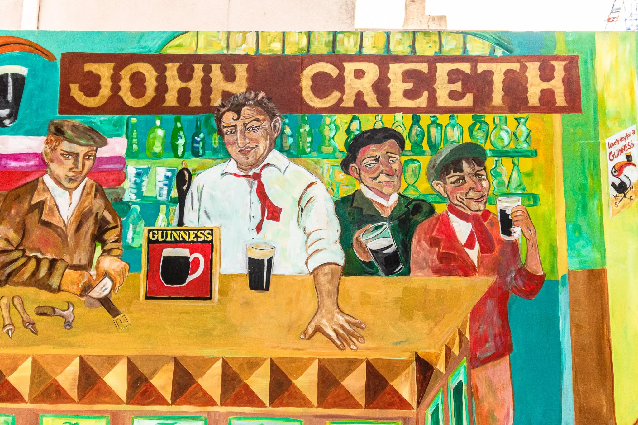 Colorful painting of four men at a bar counter, with bottles on shelves behind them. The sign above reads 'JOHN CREETH'. The man on the far right is holding a pint of Guinness, and there is a Guinness sign on the counter. The other men are engaged in