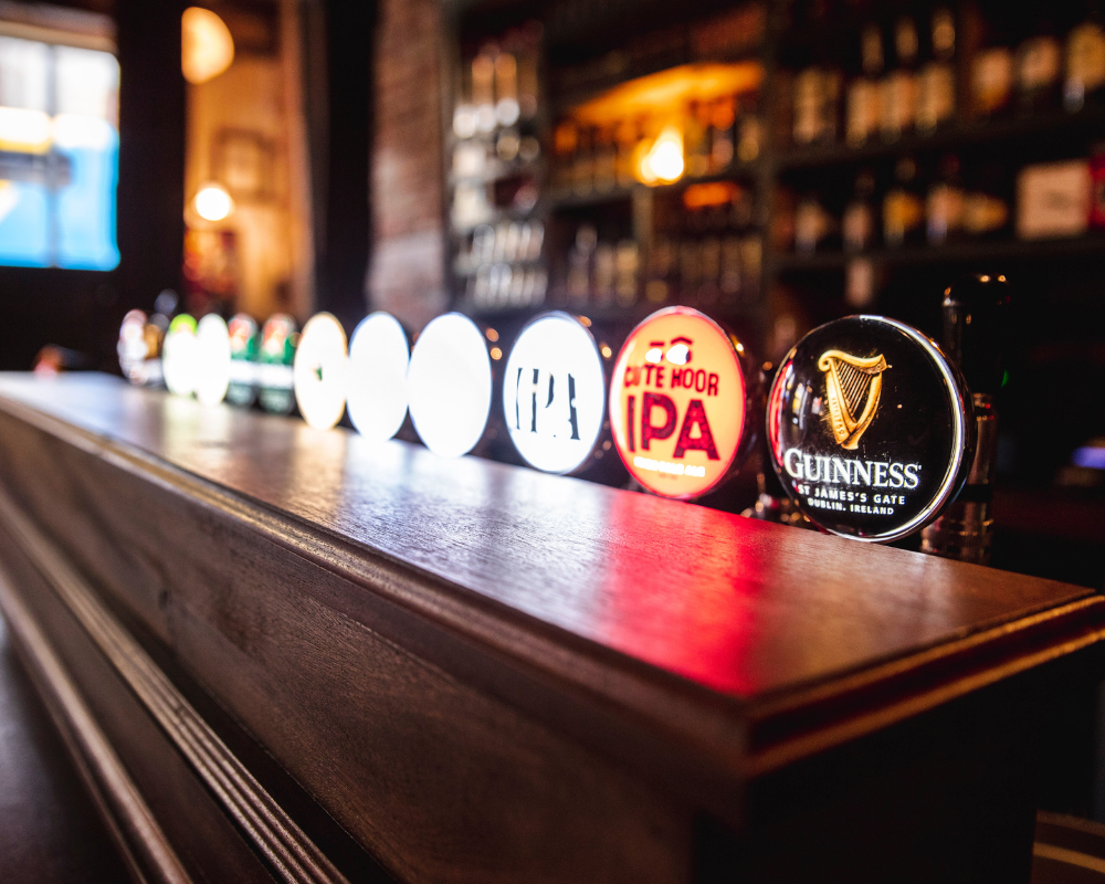 Close-up of illuminated beer tap handles on a bar counter.