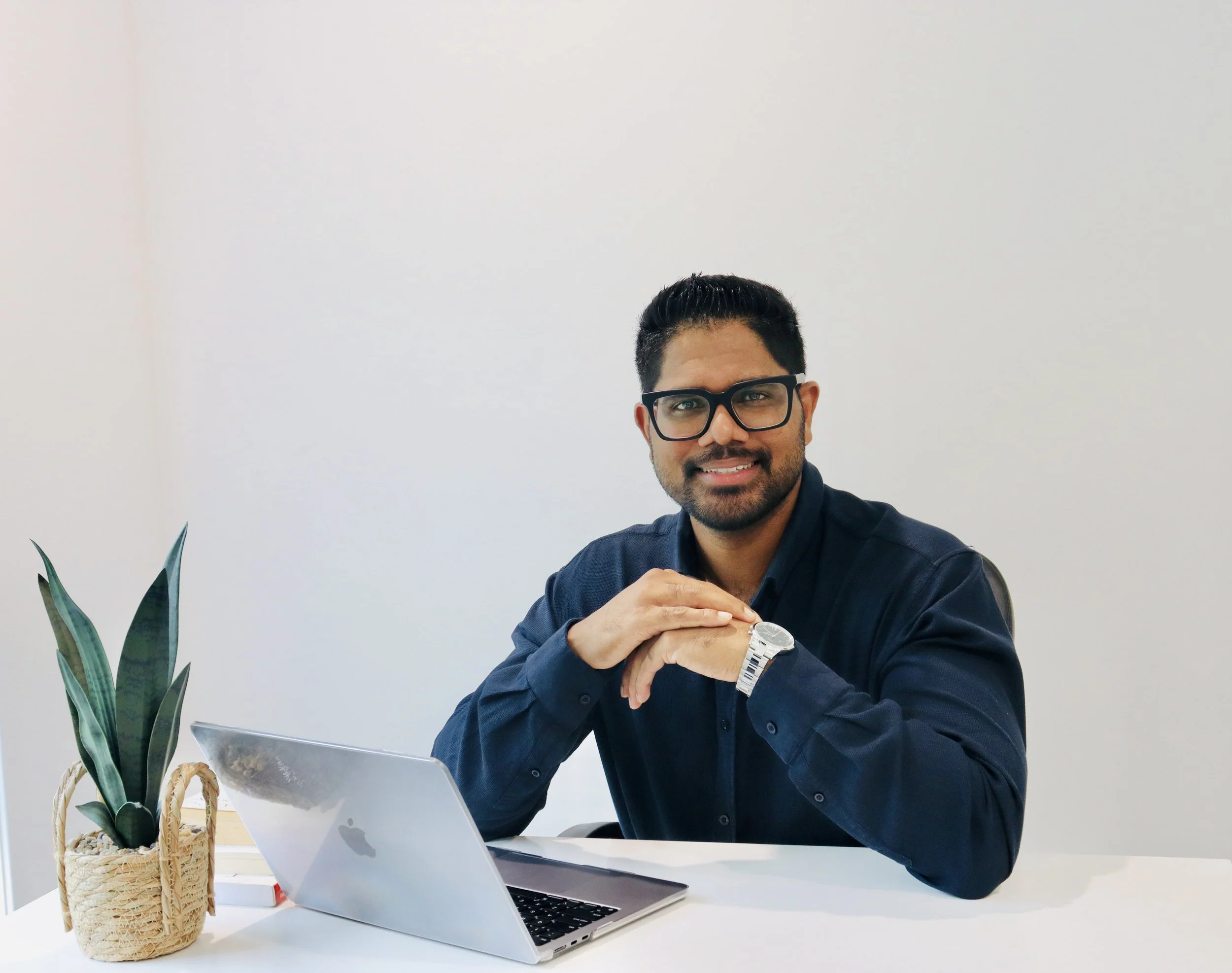 A psychologist sitting at a desk with a laptop in a professional office, representing psychological assessment and therapy services.