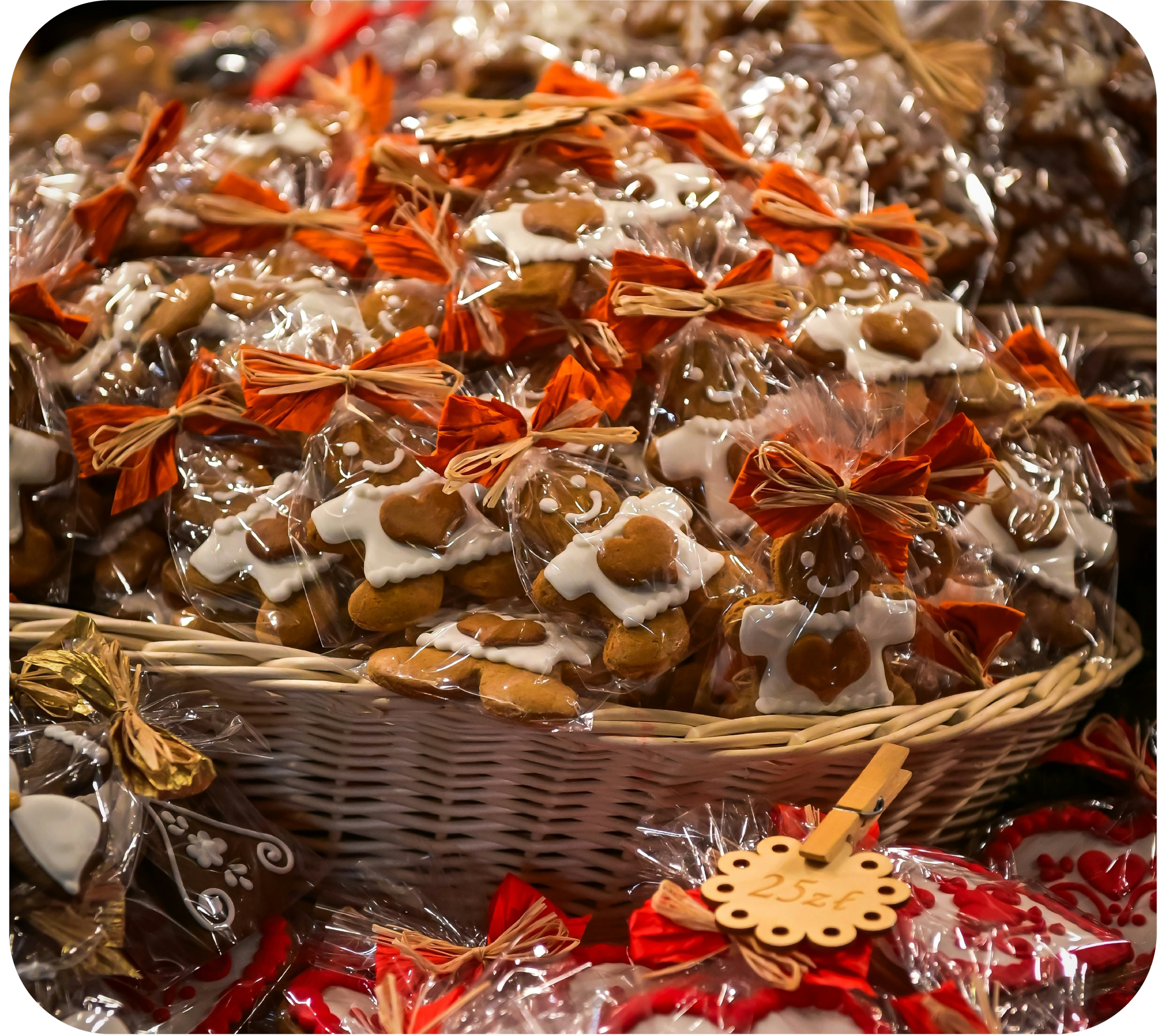 A basket filled with wrapped Christmas cookies decorated with white icing and red and gold ribbons.