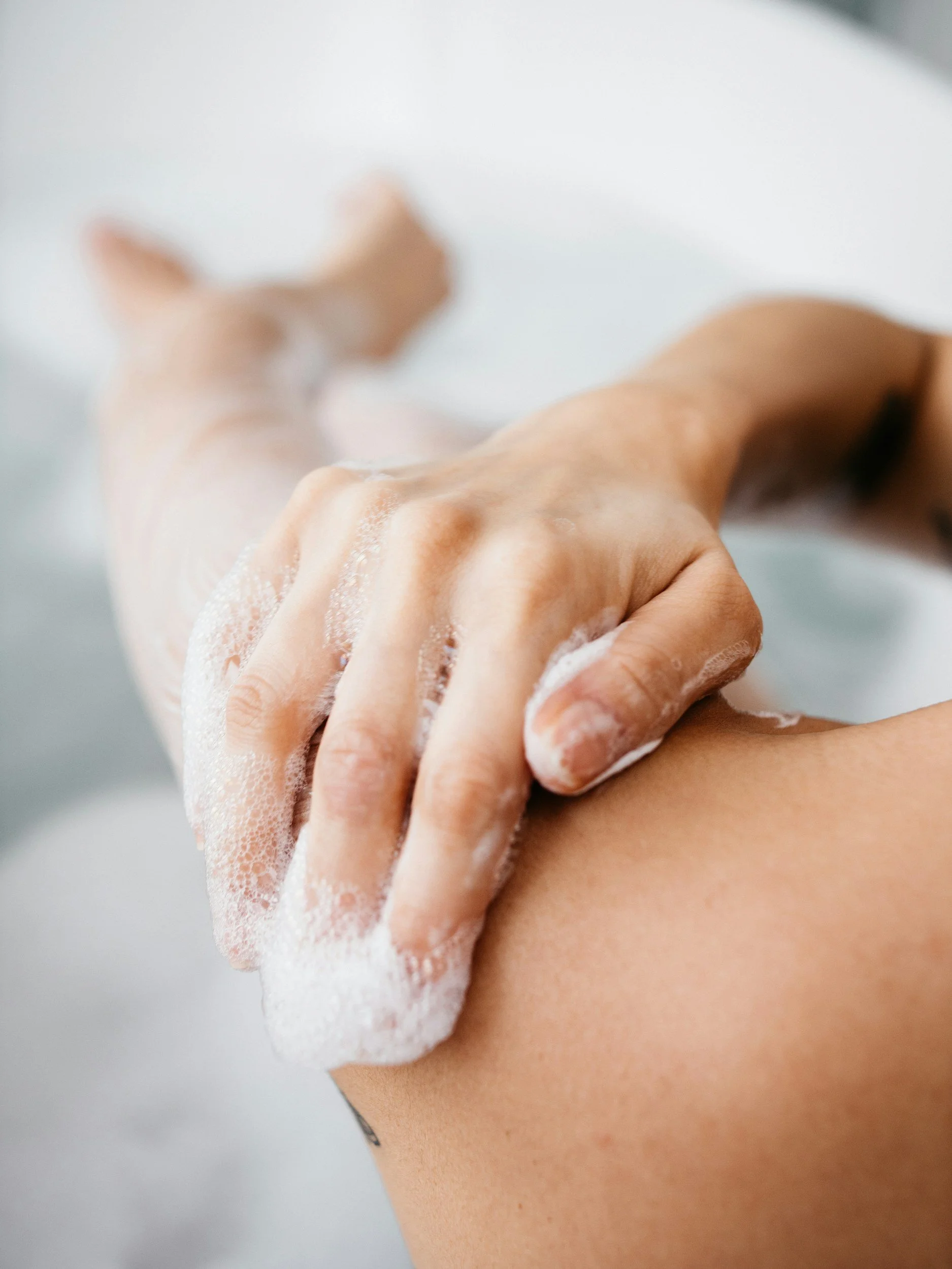 Close-up of a person washing their arm with soap lather.