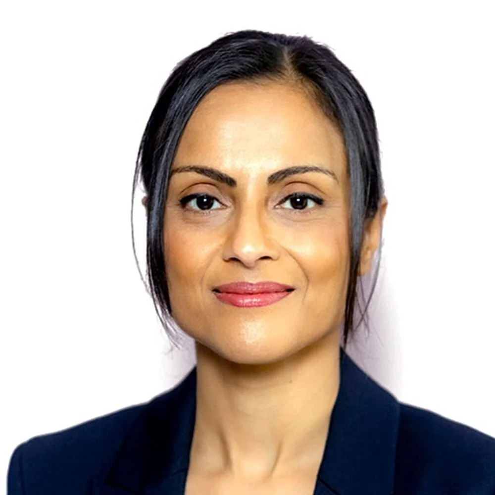 Professional woman with dark hair and a slight smile, wearing a dark blazer, against a white background.