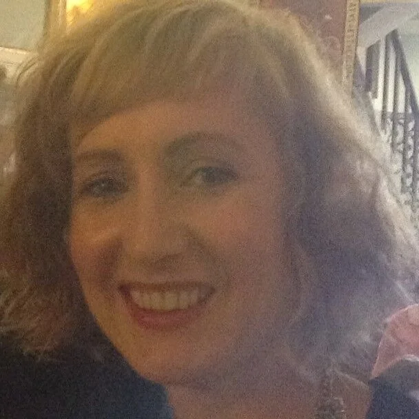 A woman with curly blonde hair smiling at the camera.