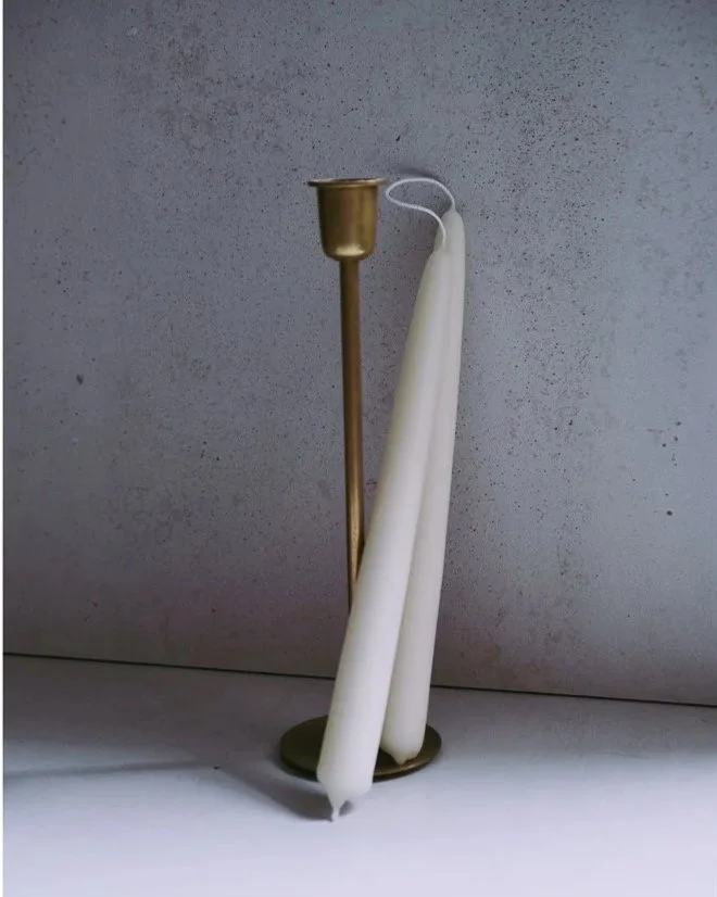 Deux bougies allumées avec une chandelle campanie en arrière-plan.