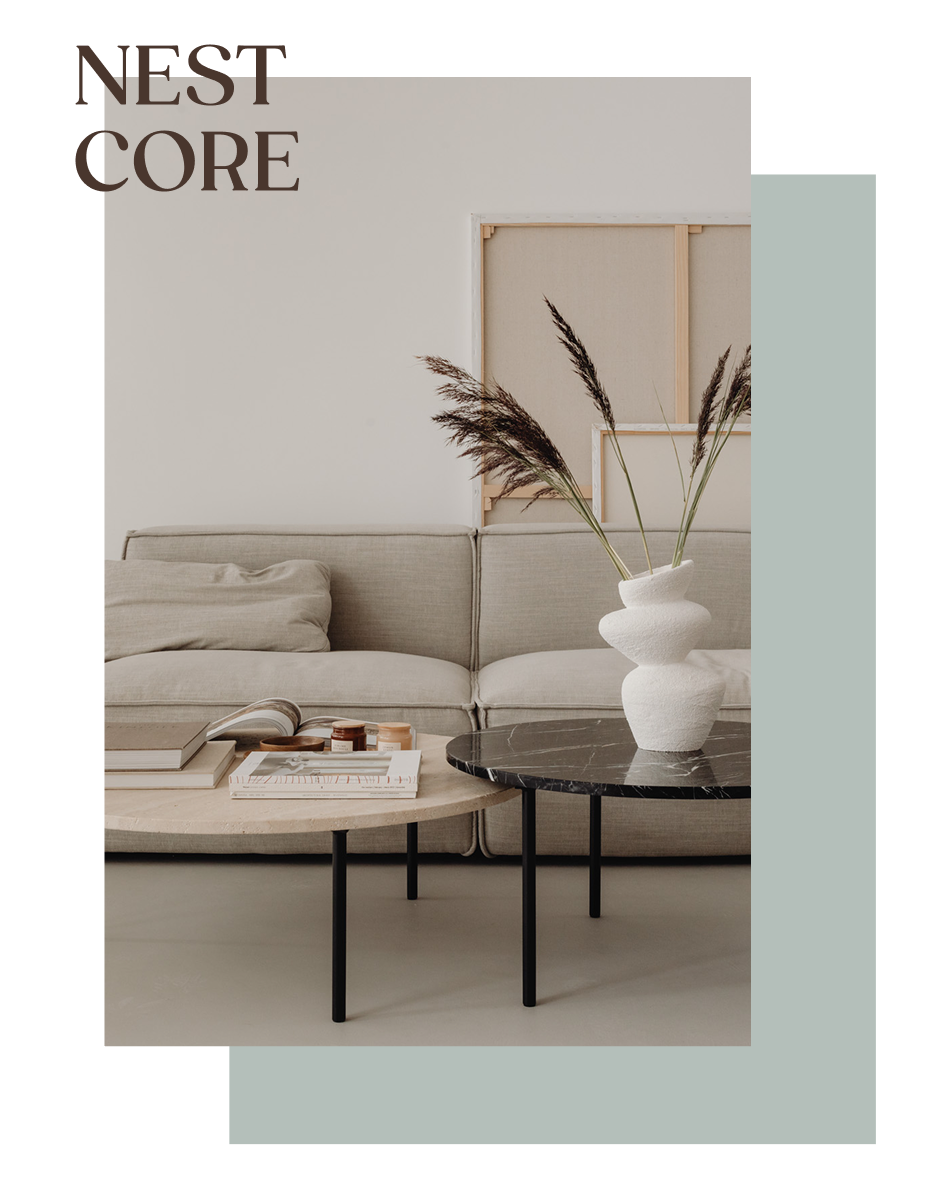 Sala de estar moderna con sofá beige, mesa de centro con libros y objetos, y jarrón blanco con ramas secas en un ambiente minimalista.