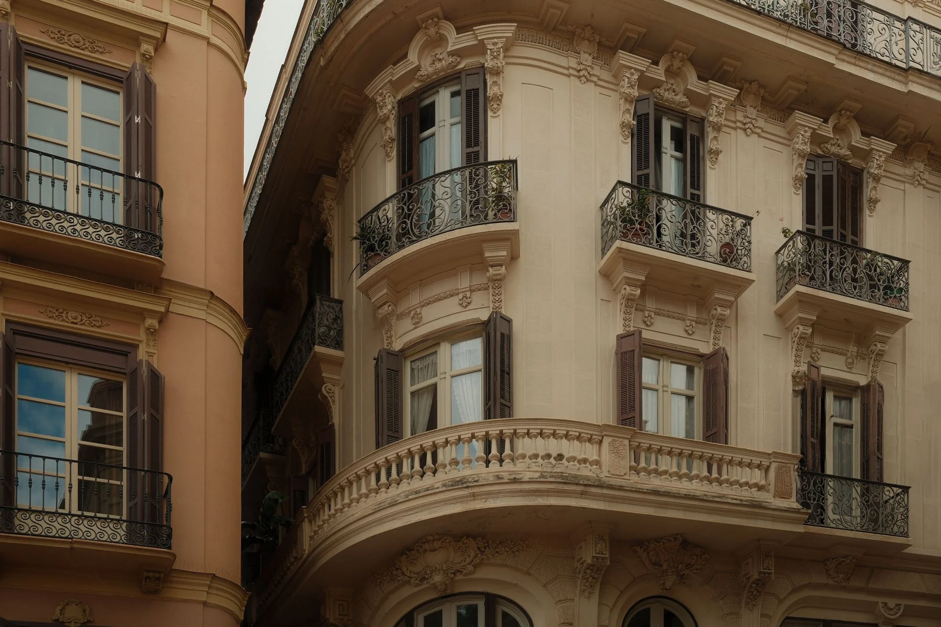 Edificio antiguo con balcones de hierro forjado y ventanas con madera, detalles ornamentales en la fachada, estilo clásico europeo.