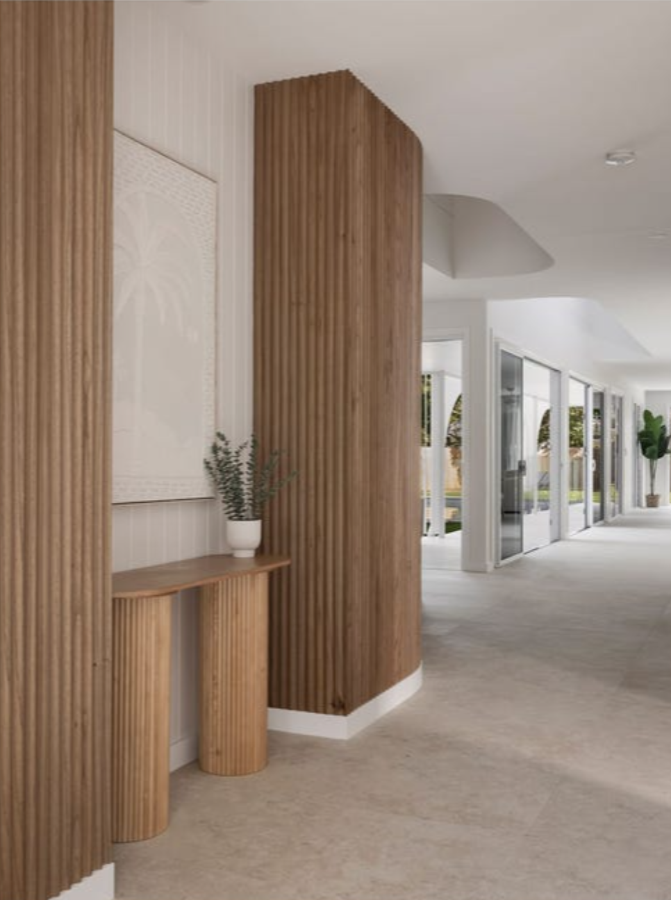 Modern interior hallway with wood panel accents, sliding glass doors, and potted plants.