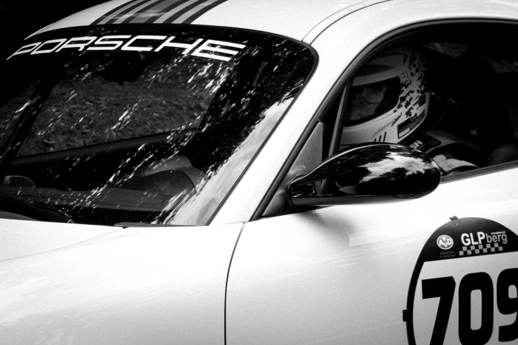 Person mit Rennhelm im Cockpit eines weißen Rennwagens.