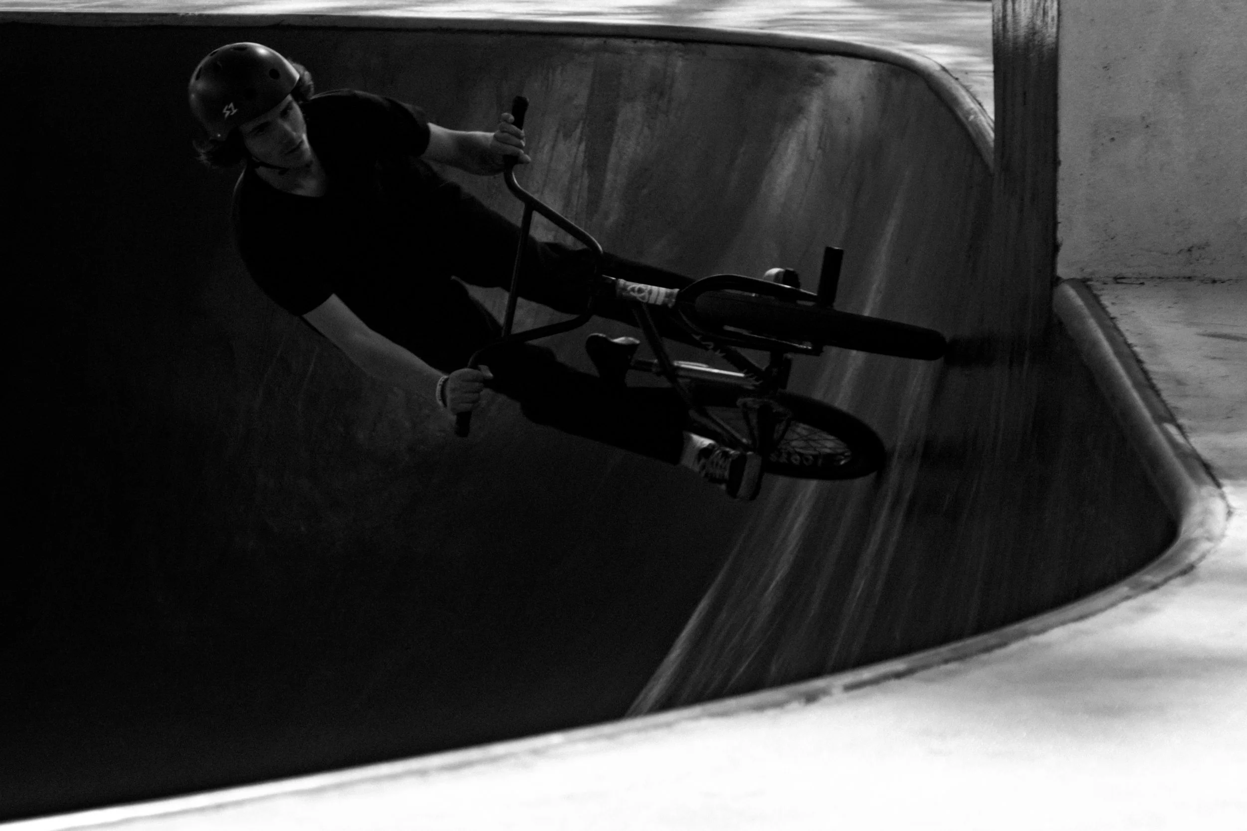 Person auf einem BMX-Rad in einer gebogenen Skatepark-Rampe.