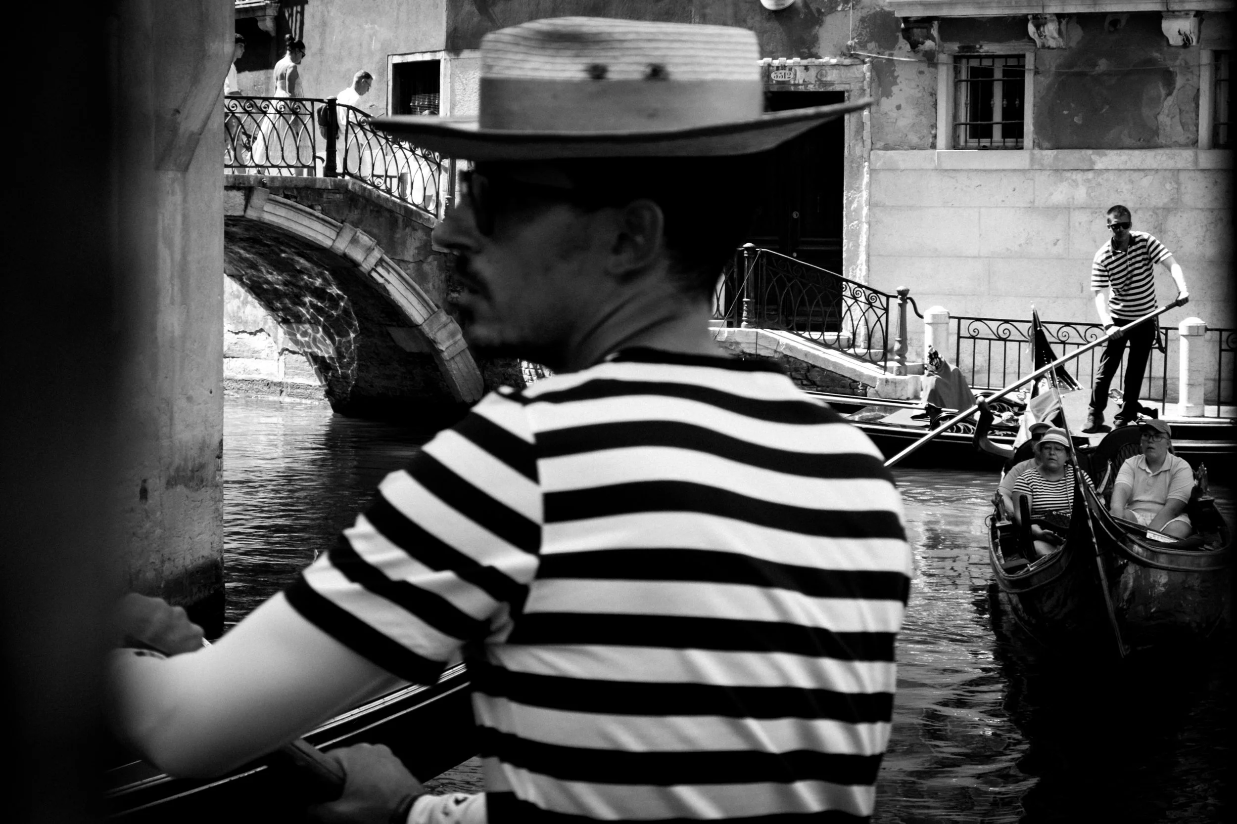 Person mit gestreiftem Shirt und Strohhut an einem Boot auf einem Kanal.