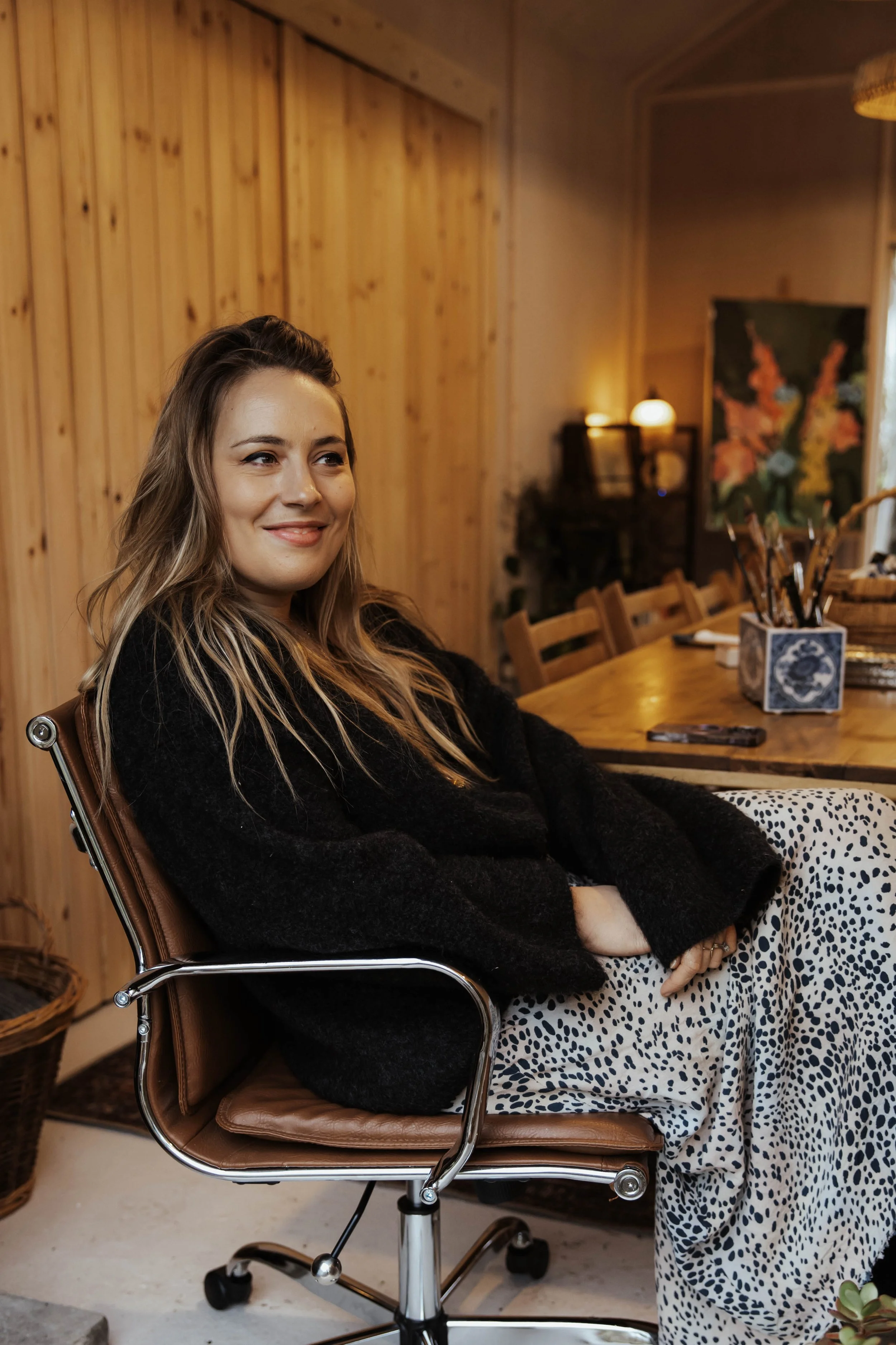 Hannah Taylor-Matthews, founder of A Creative Pause sitting in desk chair and smiling at camera